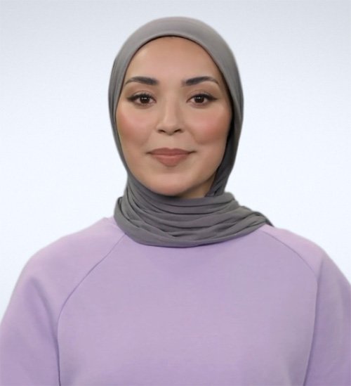 Portrait of a young woman wearing a gray hijab and a lavender top, smiling gently against a plain white background.