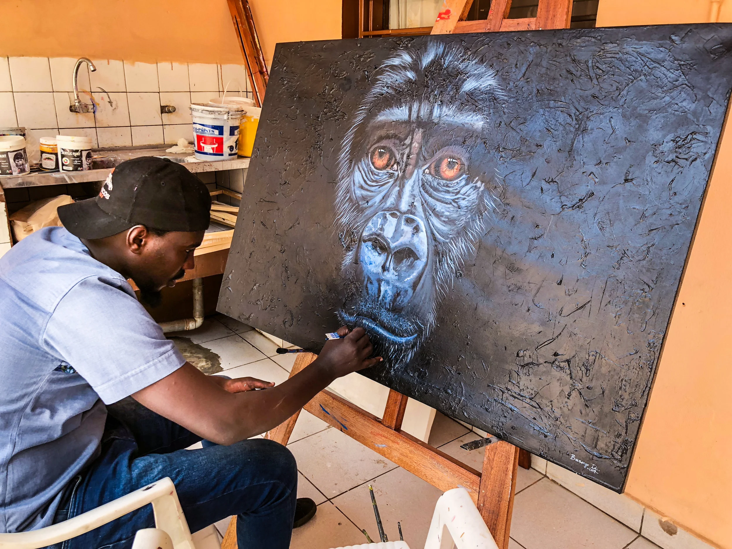 Idi finishing up his acrylic piece titled “Soul of Rwanda”