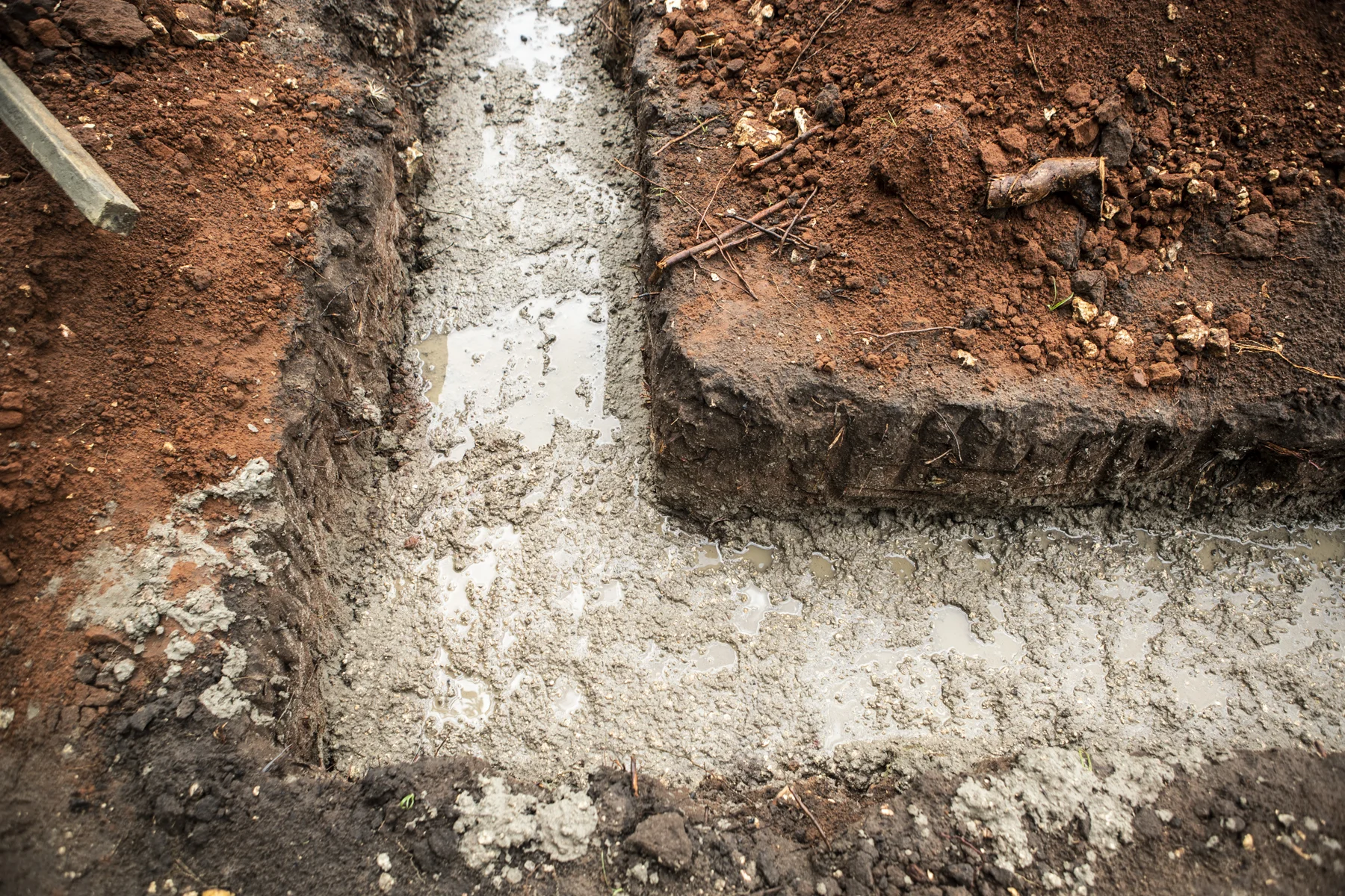Das Fundament ist fertig gegossen. Starker Regen zwingt die Fundis zur Pause.