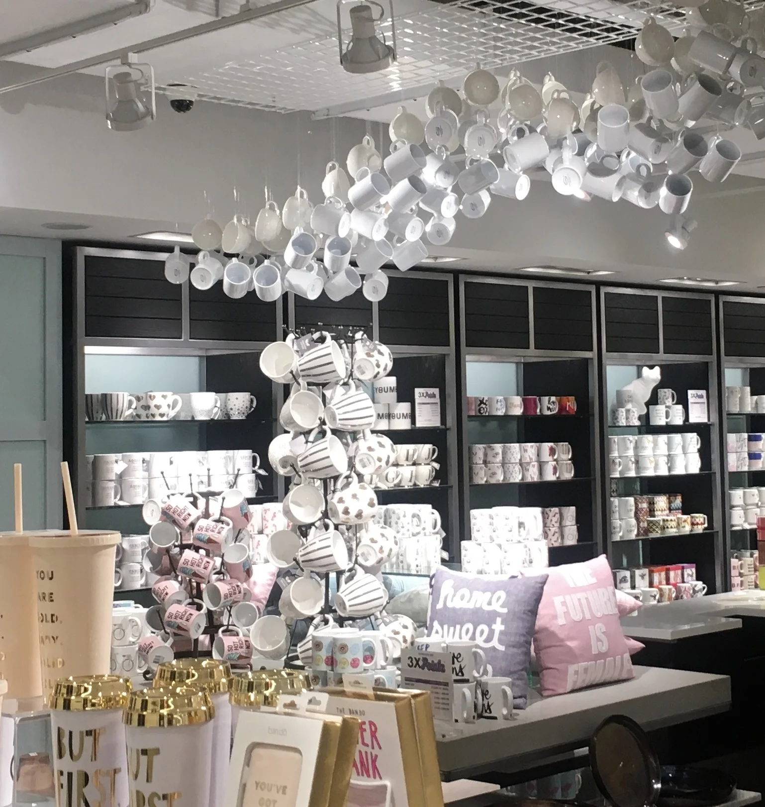 Mugs hang from a grid in wave formation in a giftware and stationary shop