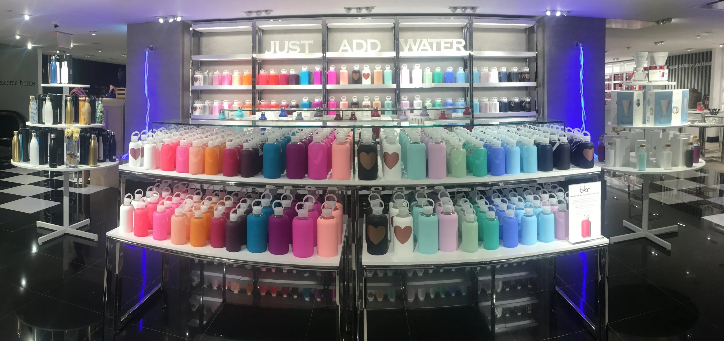 Water simulated with neon rope coming out of a faucet into a bucket and the dimensional letters “JUST ADD WATER” to create a whole shop just centered around water bottles and accessories