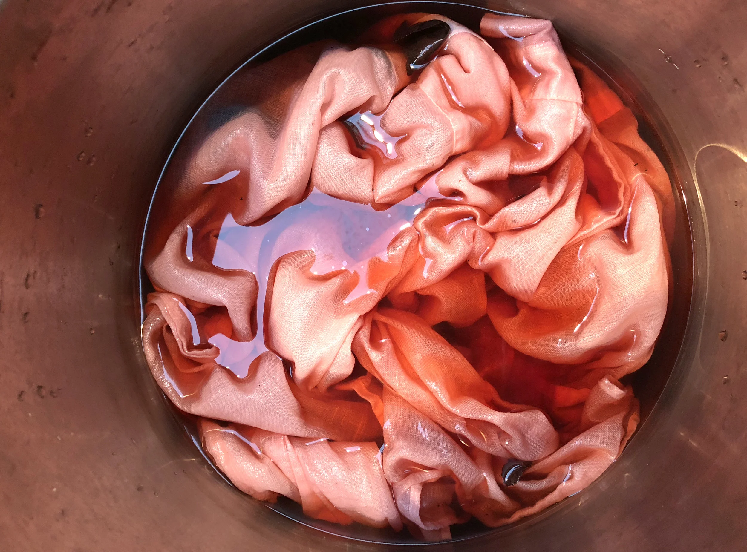 Dyeing linen in a dye bath made from avocado pits.