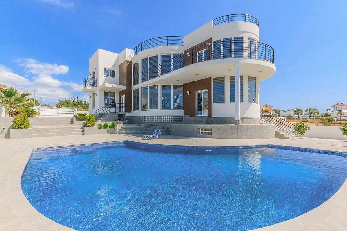 Vista de una casa moderna con piscina y patio en un día soleado