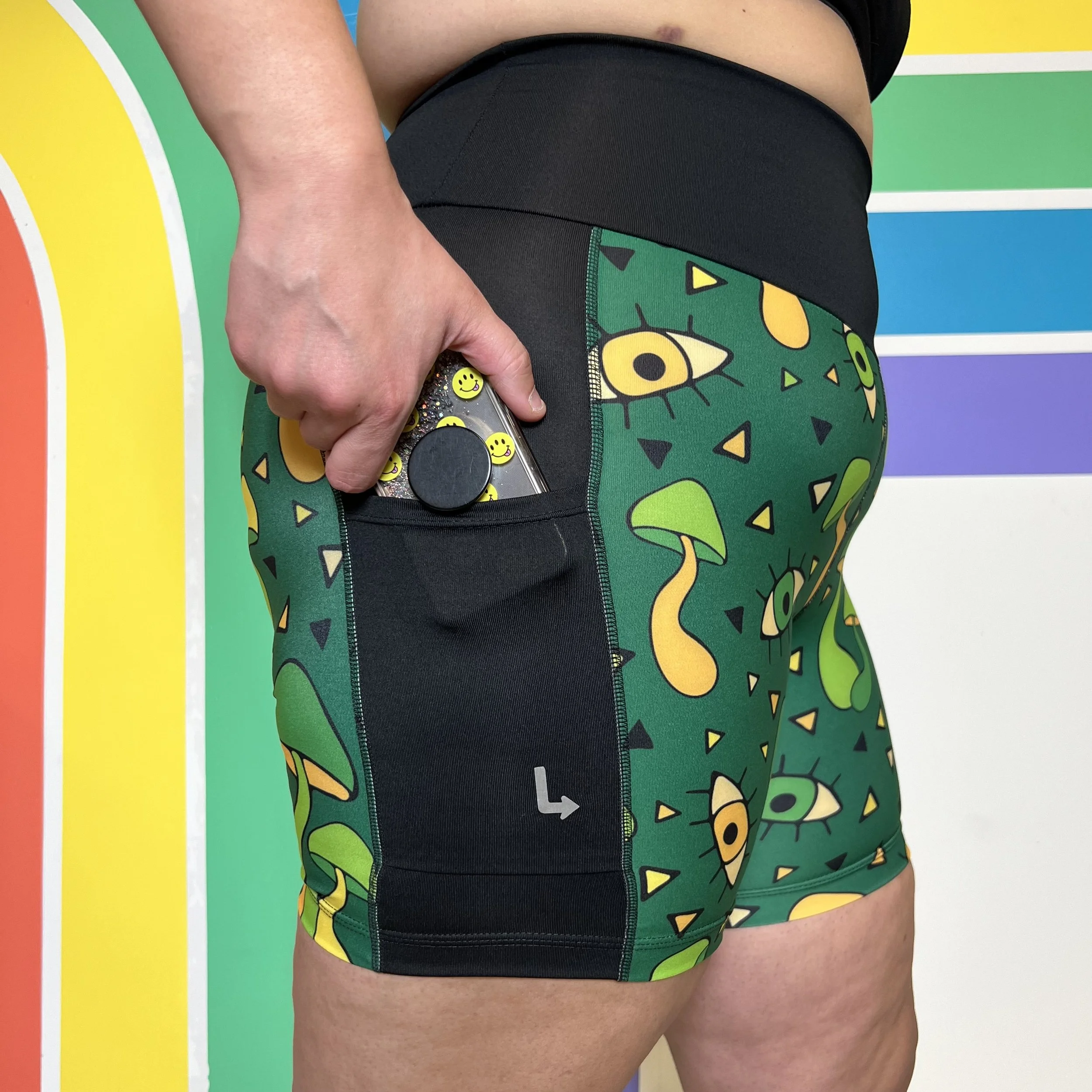 Side view of mushroom trip pocket bike shorts by Left Turn Clothing. A mobile phone is held halfway out of the pocket.
