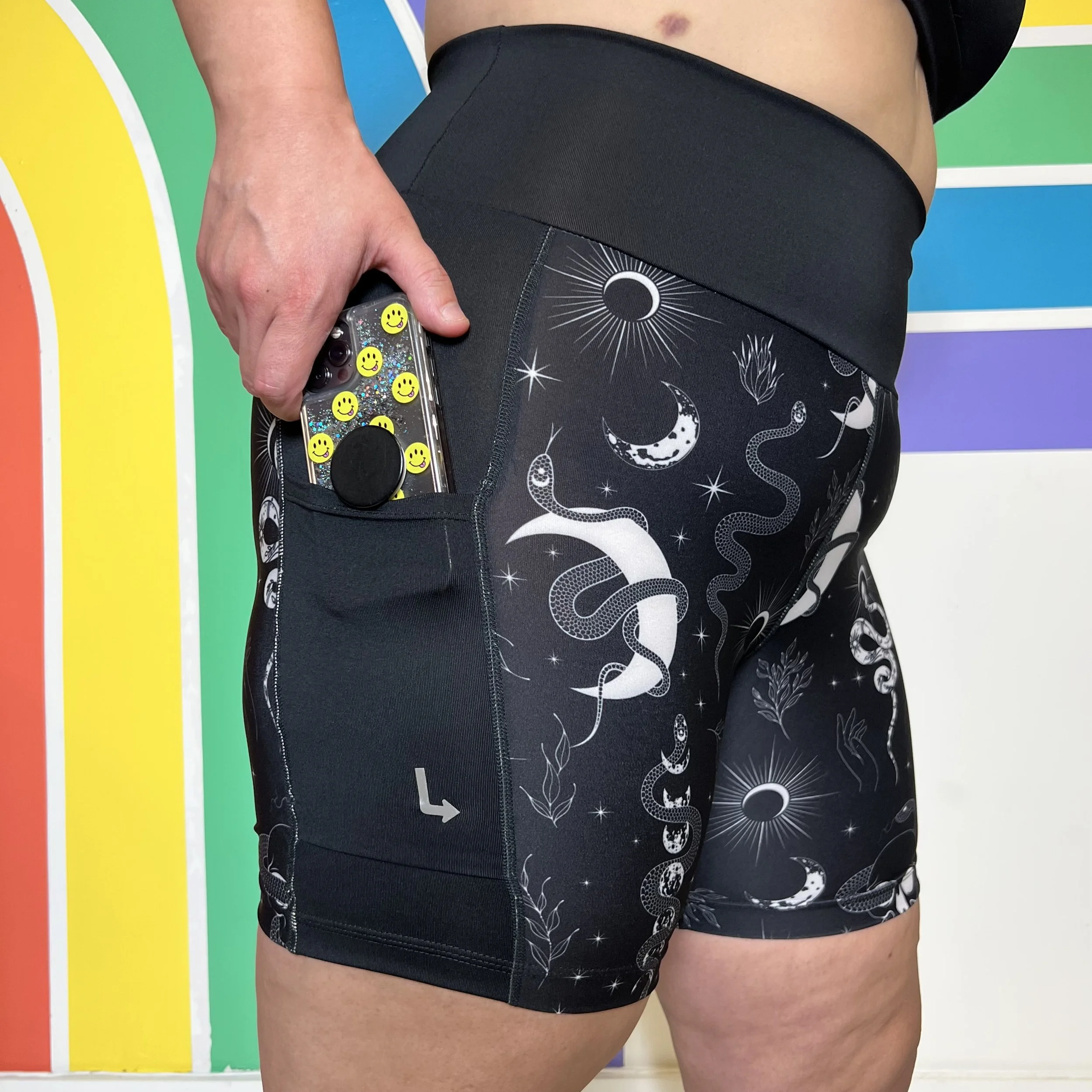 Side view of occult pocket shorts from left turn clothing. A mobile phone is held halfway out of the pocket.