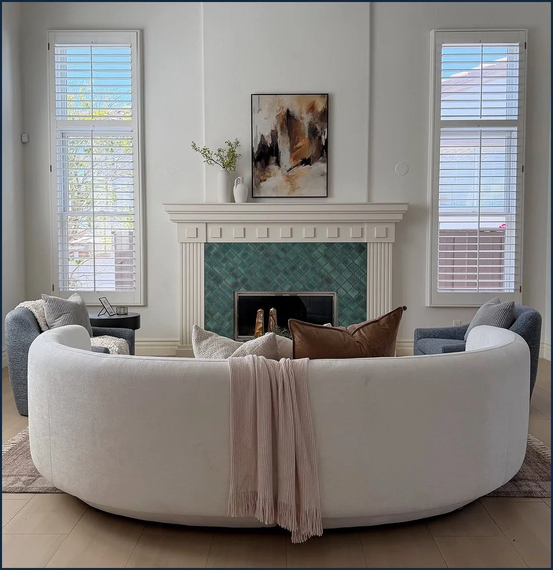 Staged San Diego living room with a curved sofa in front of a turquoise tiled fireplace, by CASA BY CRAFT