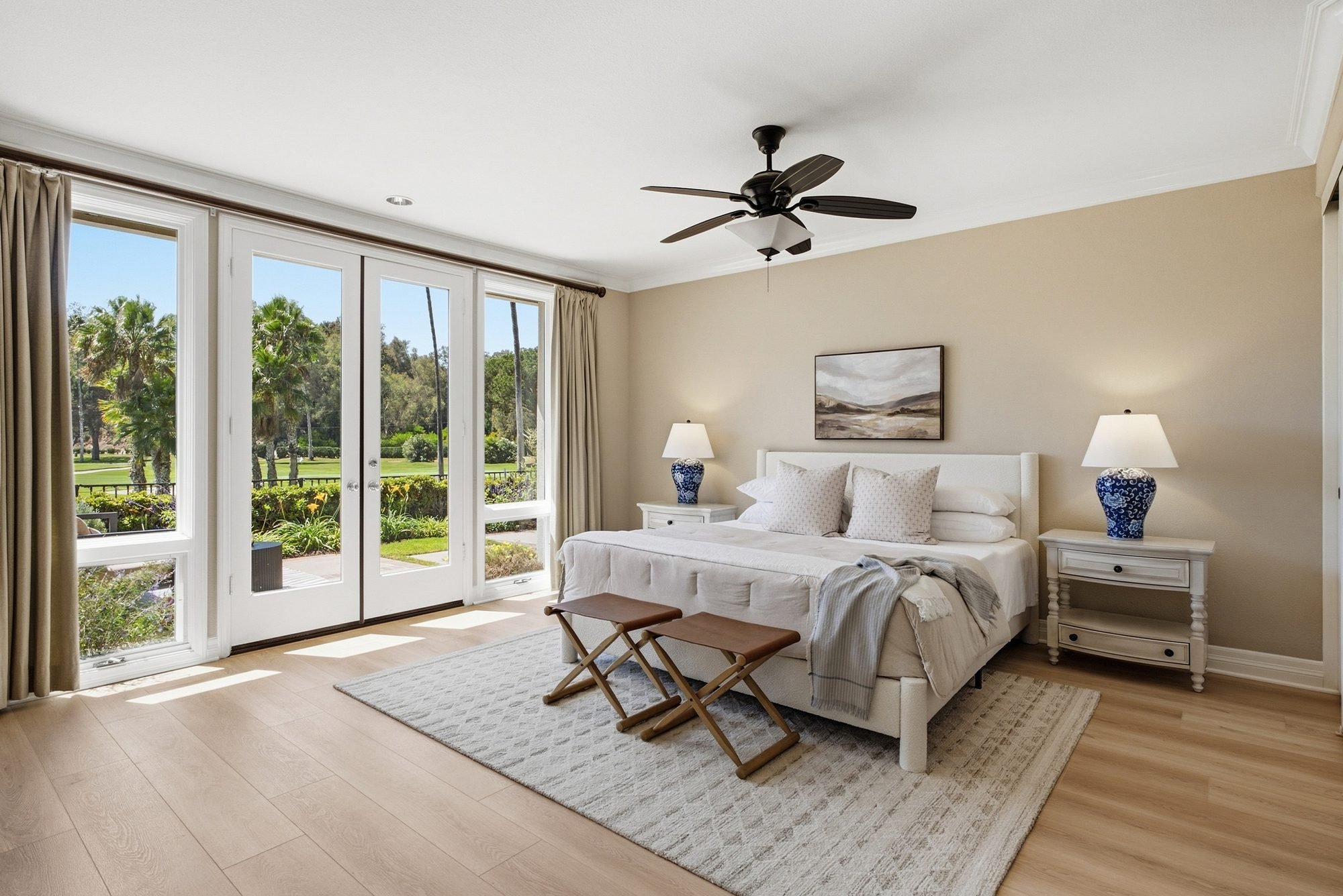 Staged primary bedroom with blue lamps and French doors, styled by CASA BY CRAFT for a San Diego real estate listing