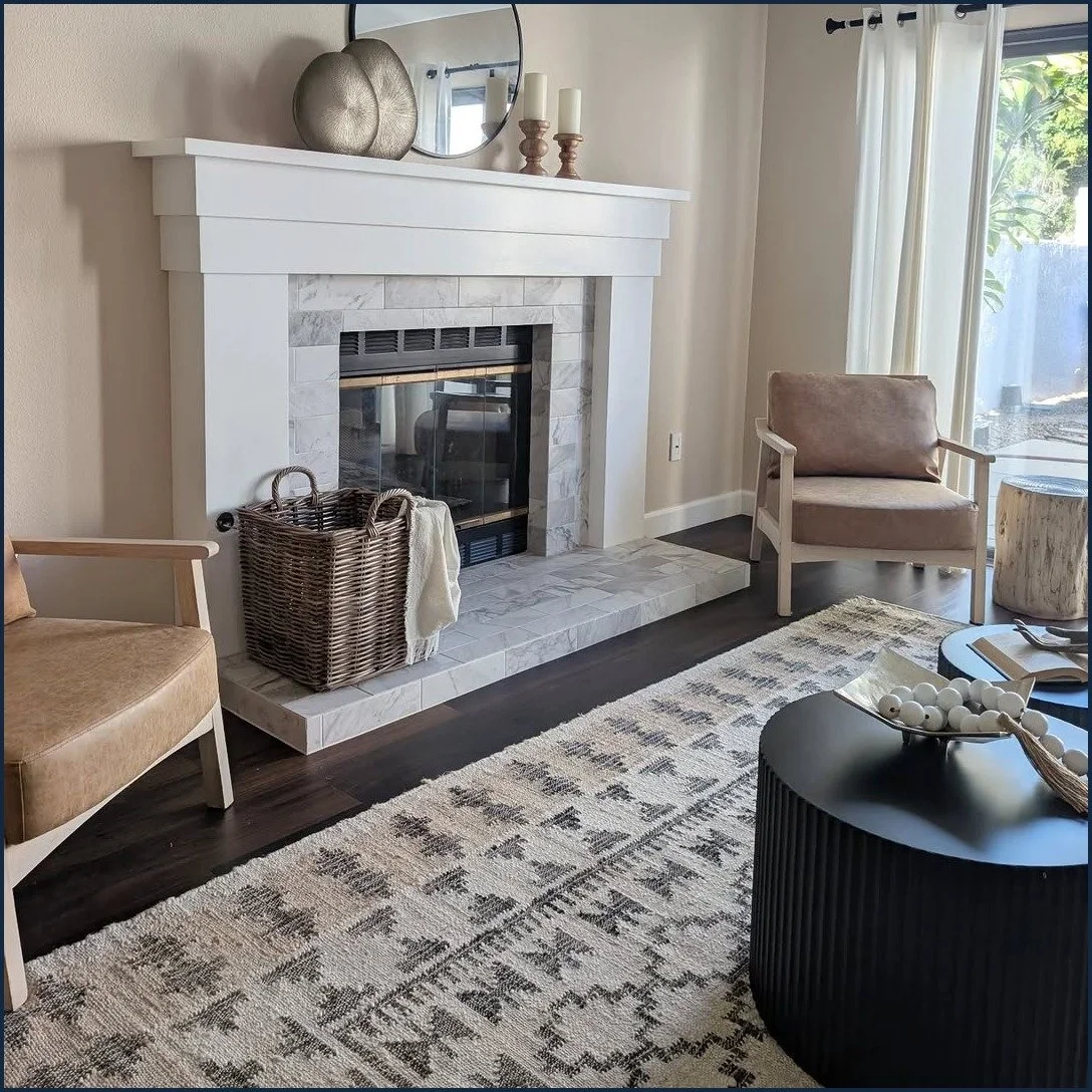 Carlsbad condo fireplace staged with a round mirror, brass accents and wood candlesticks