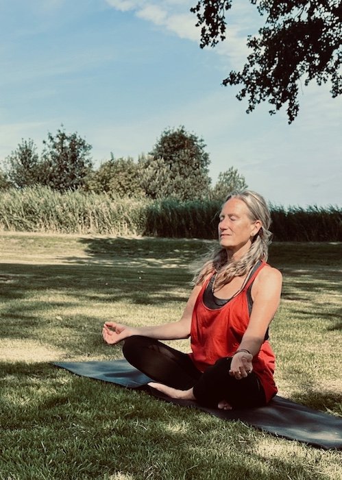 Deelnemer aan buiten yoga in meditatiehouding in de natuur
