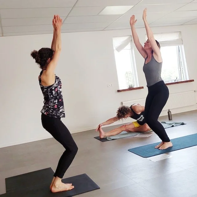 twee vrouwen in stoelhouding (uttkatasana) tijdens yogales