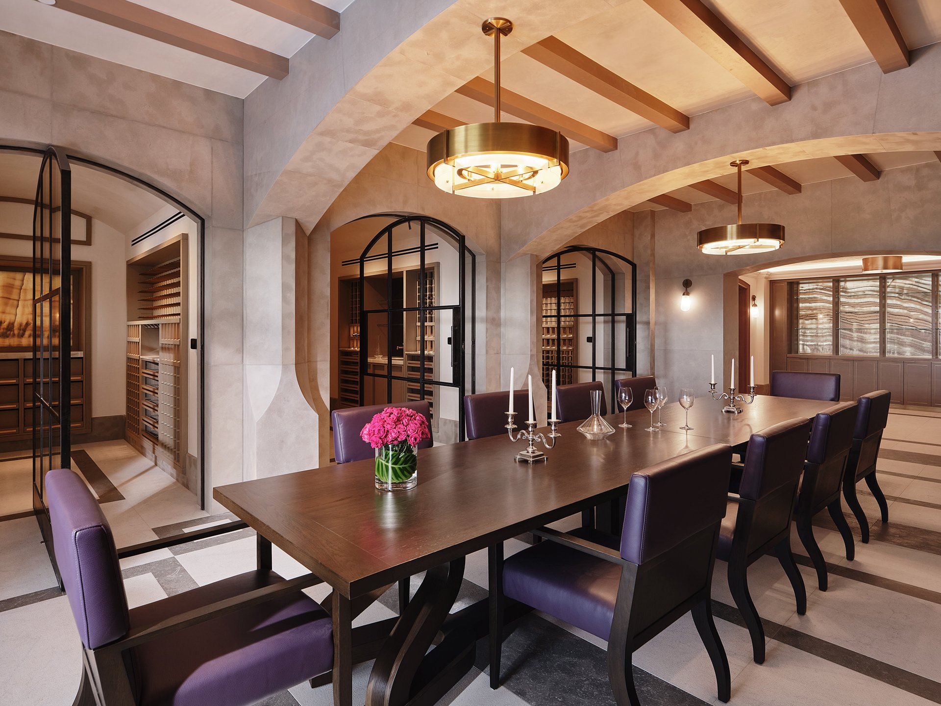 Elegant dining room with vaulted ceilings, exposed beams, long wooden table, purple chairs, and arched wine cellar doors