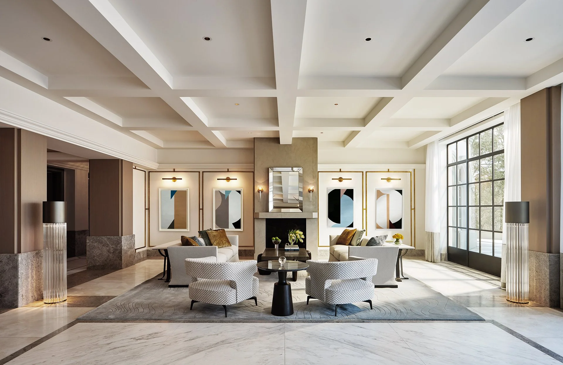 Elegant contemporary living room featuring coffered ceilings, modern art, plush seating, and rich marble flooring.