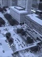 Dark electronica Synth music Bird's eye view of a city street with buildings, trees, and vehicles.