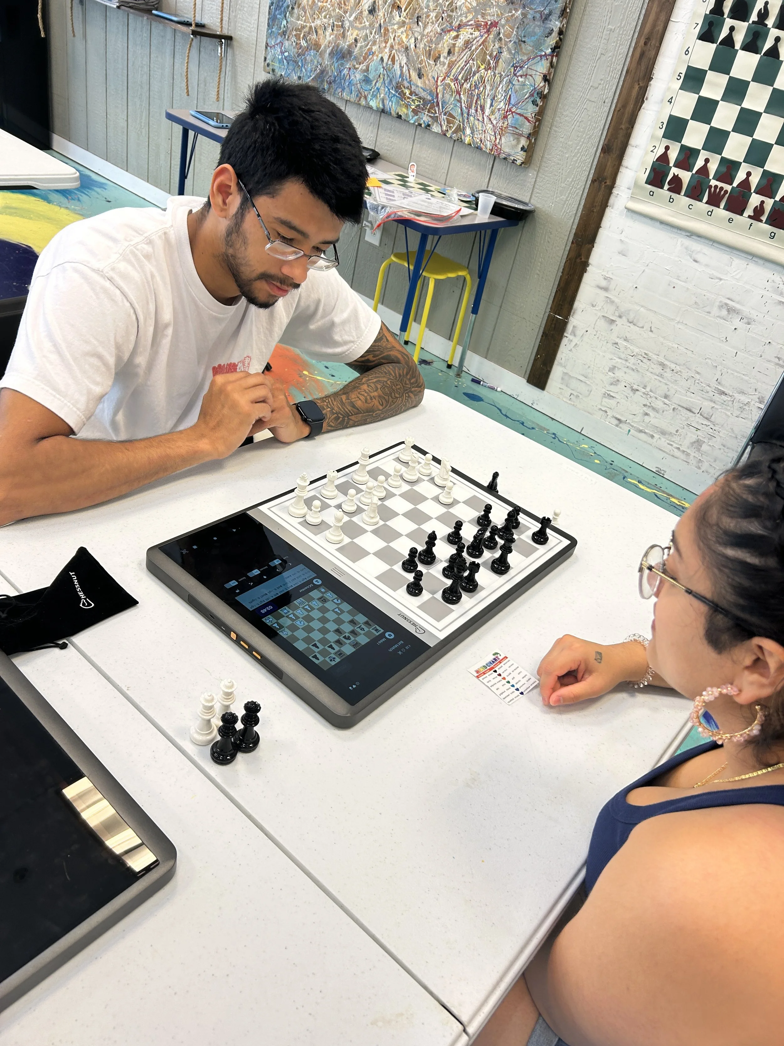 A chess match in progress with friends cheering nearby