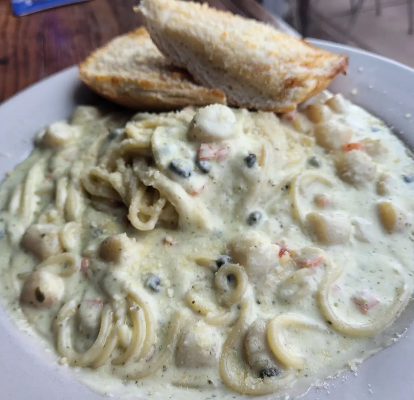 Bay scallops in a creamy pesto sauce with tomatoes, capers, and spaghetti noodles