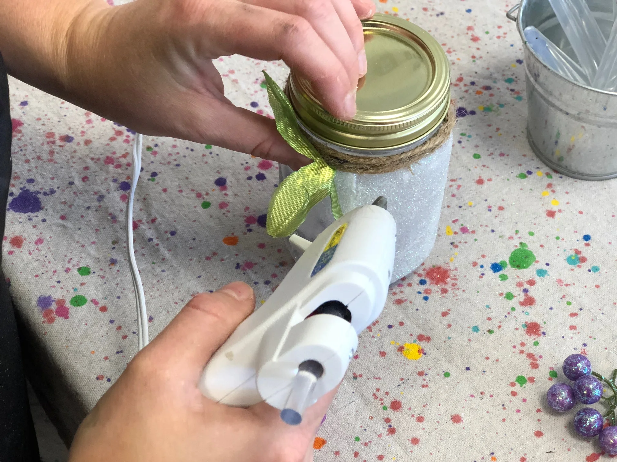 How to make a light up glittery fairy jar lantern. Use a smooth mason jar, glitter, and tea light to make your own light up fairy lantern. Add some floral accents and you have a perfect fairy jar night light for your fairy obsessed little girl.