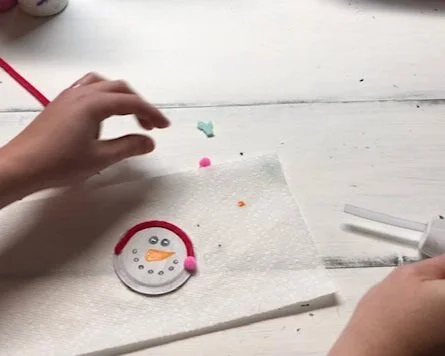 DIY snowman made from a mason jar lid. How to make cute snowmen Christmas ornaments from a lid from a mason jar. Easy craft tutorial to make fun ornaments for kids.
