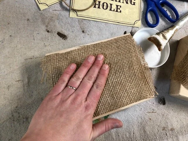 How to apply fabric and burlap to wood. Watering hole wild west table sign. DIY western party table decor. Free printable