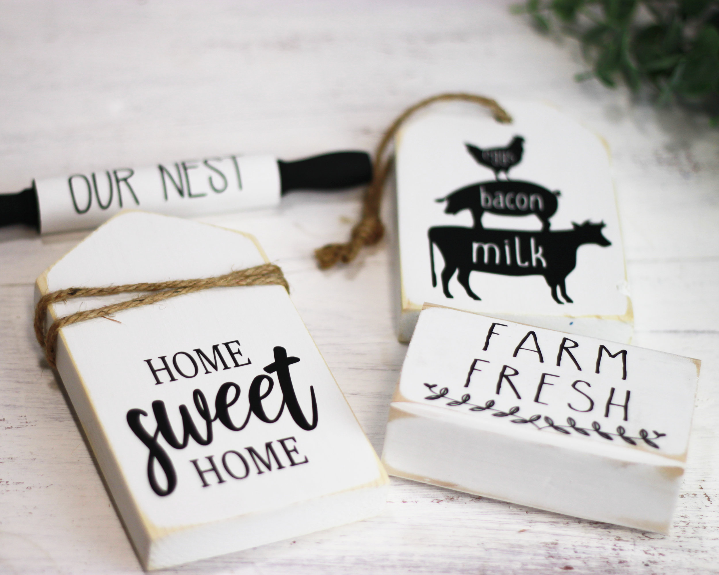 Tiered tray signs for rustic home decor. Classic style mini wood signs in white and black. Sign bundle comes with home sweet home, farm animal trio of chicken pig and cow on a rustic wood tag, mini rolling pin our nest, and farm fresh.