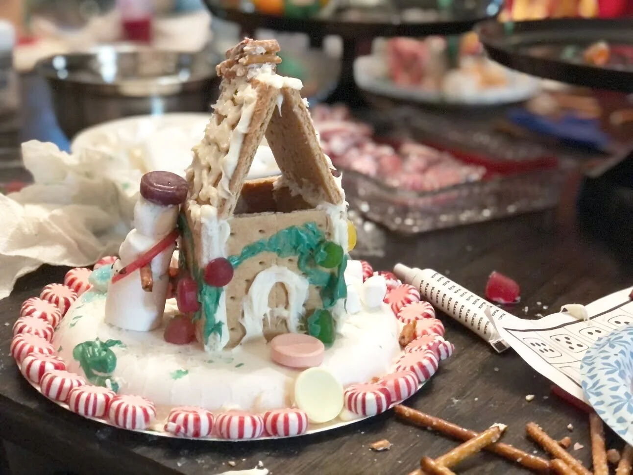 Kid friendly gingerbread house decorating party using graham crackers. How to have a stress free Christmas tradition party with your kids. Decorating gingerbread houses as a family. How to make easy gingerbread houses for kids.
