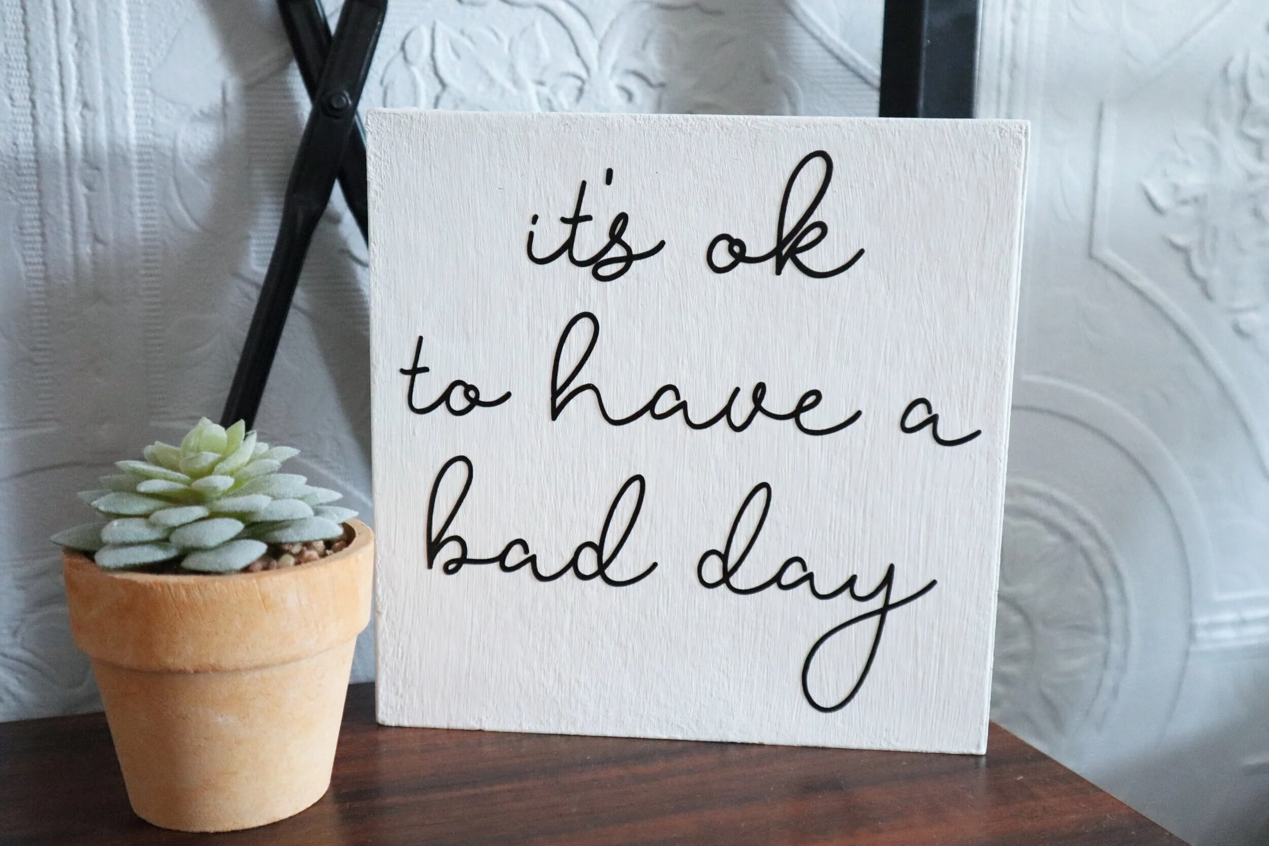 DIY dollar store sign makeover. How to give a dollar tree seasonal free standing faux wood sign a more modern look using your Cricut. DIY vinyl decal using your Cricut 'it's ok to have a bad day' diy sign.