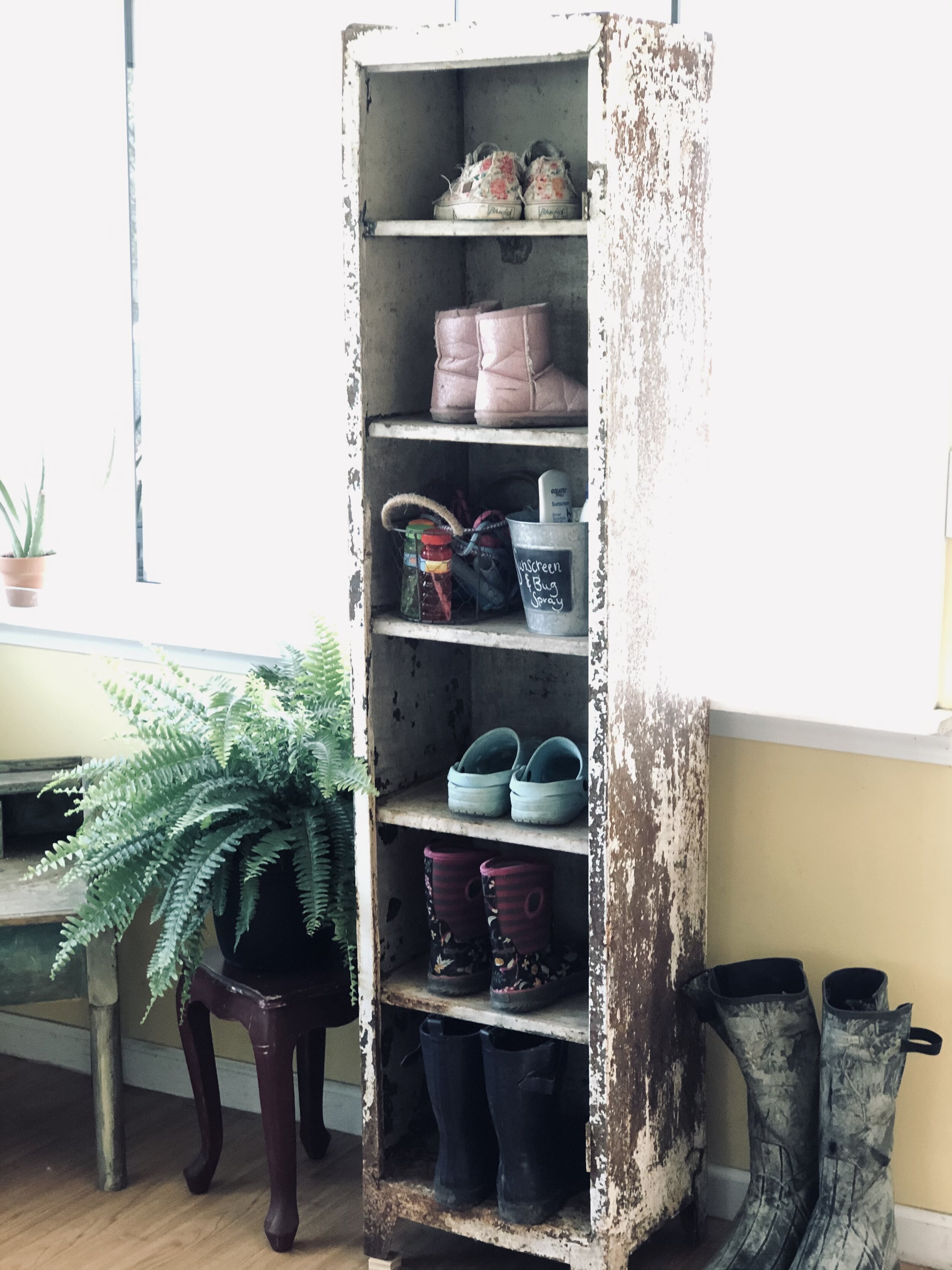 Rusty locker / metal cabinet repurposed for a mudroom sunporch. Turn an antique chipped paint locker into a shoe holder for your mudroom. Frugal rustic farmhouse furniture for your storage needs.