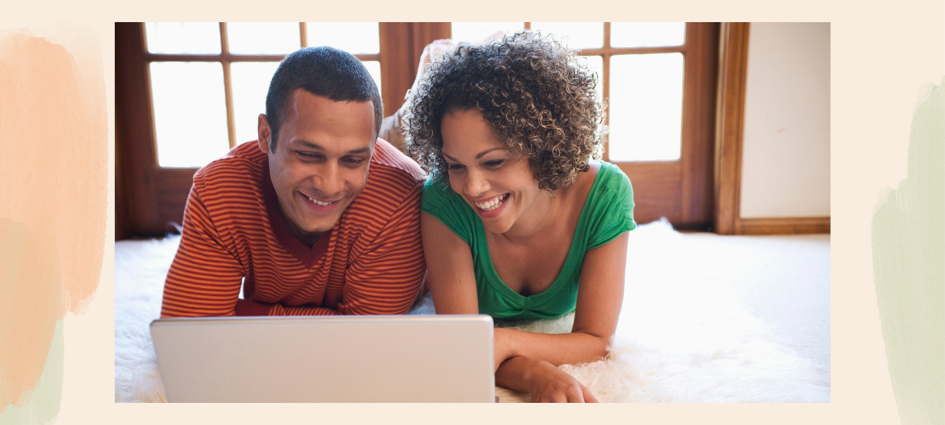Couple smiling together while using a laptop for virtual therapy at home.