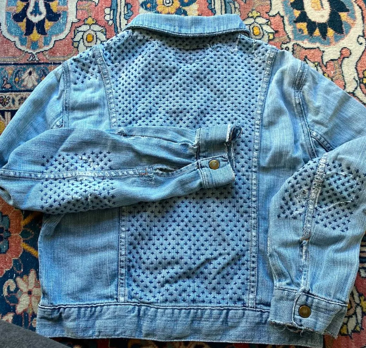 Denim jacket mended using sashiko crosses