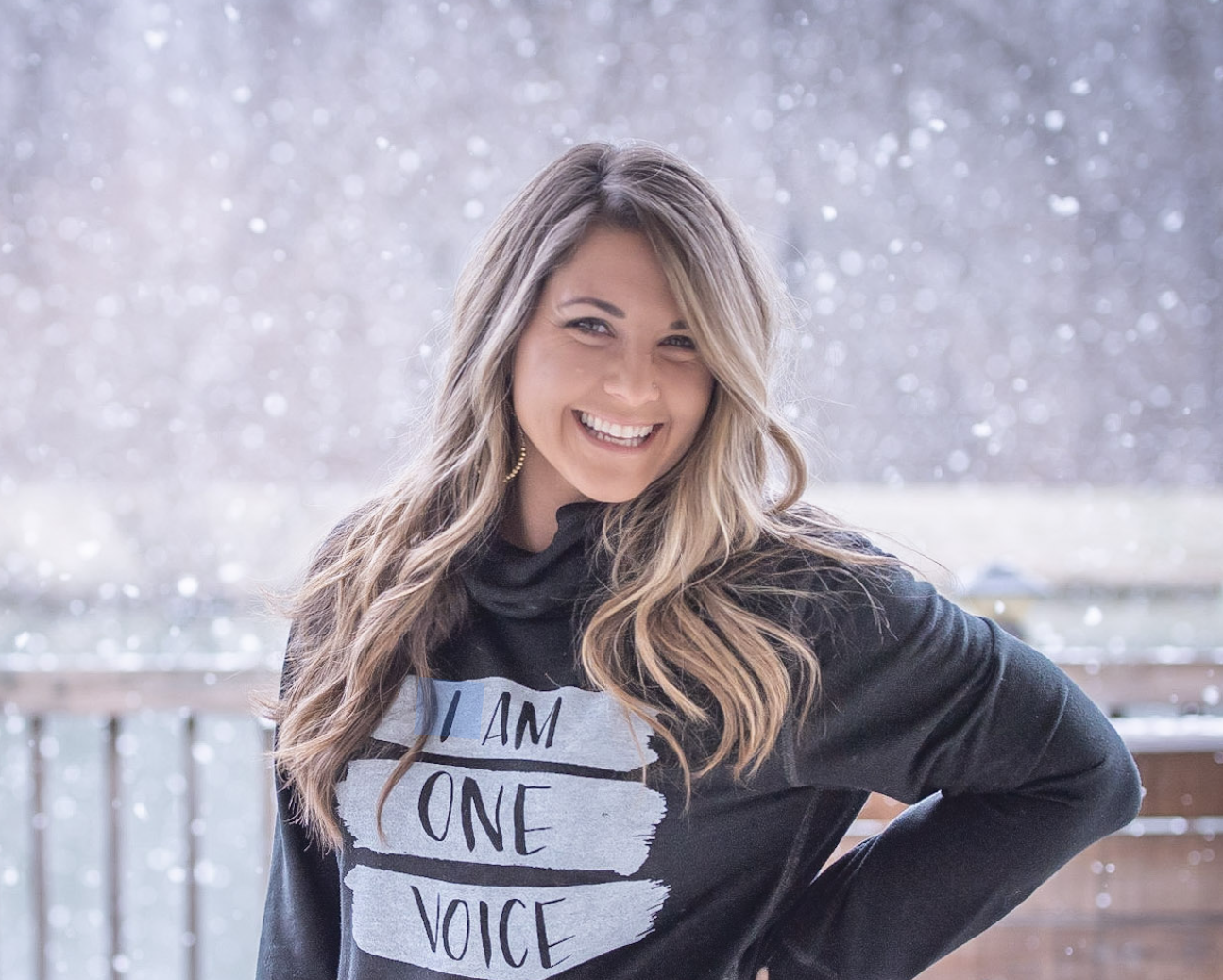A young woman with long brown hair highlighted with blonde standing in the snow