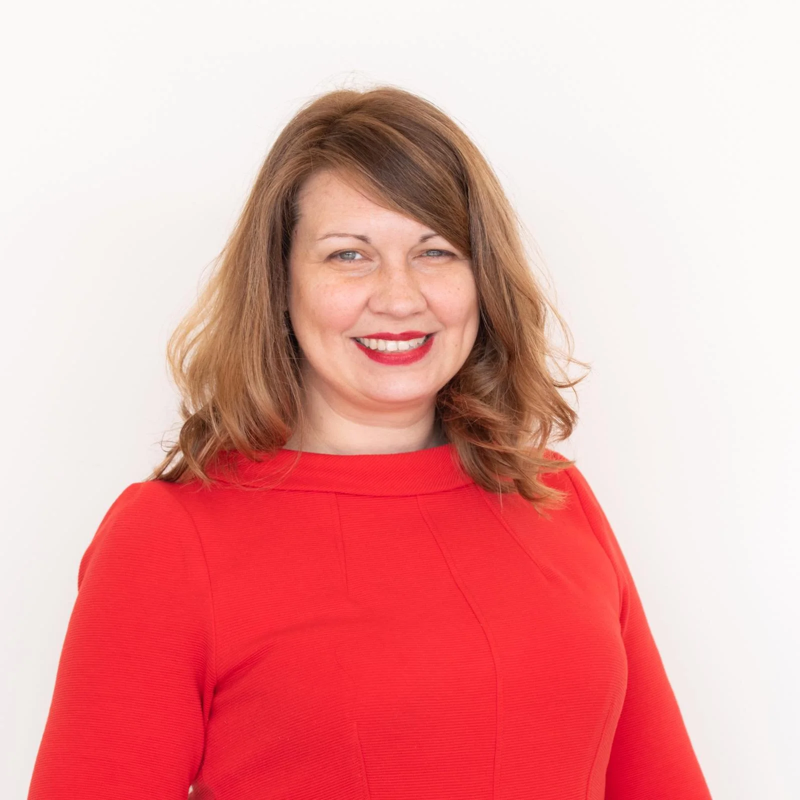 A portrait of a woman with light brown shoulder length hair in a red sweater.