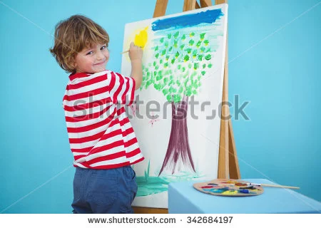 Child in a red and white striped shirt painting a tree on a canvas with green leaves and a brown trunk.