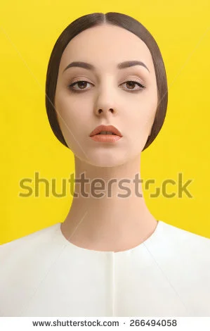 A young woman with fair skin and dark hair against a bright yellow background.