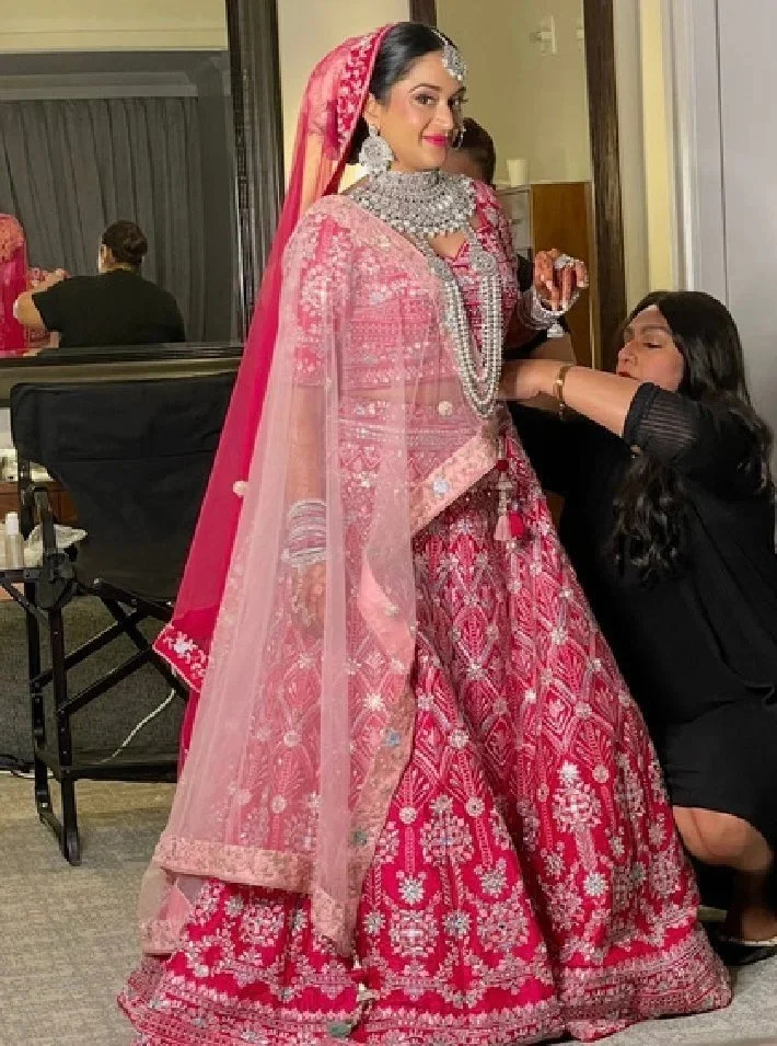 Red Lotus artist draping a bride in a pink lehenga, The 360 Experience