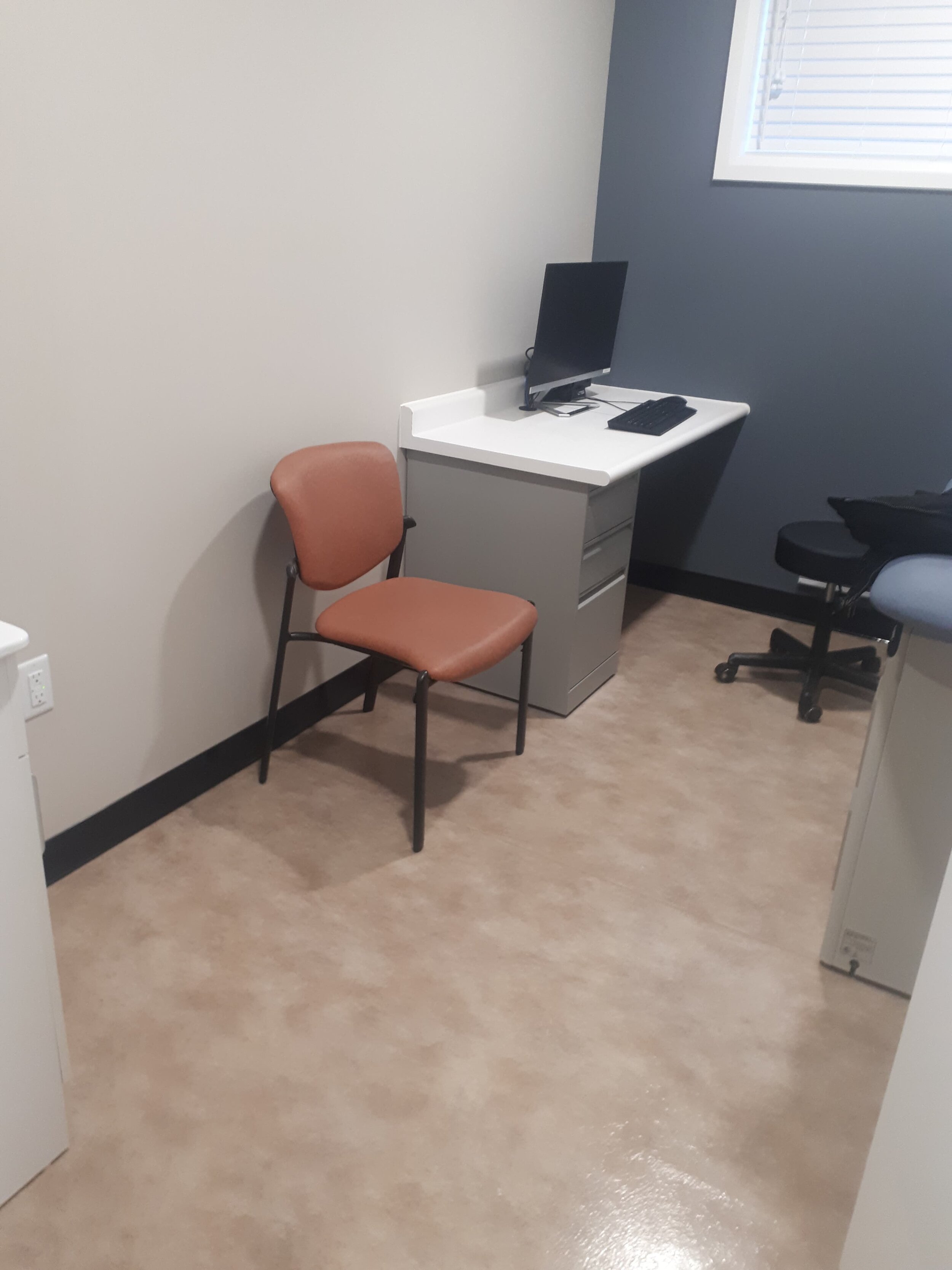 Interior of patient room with chair, table and desk  with computer. 