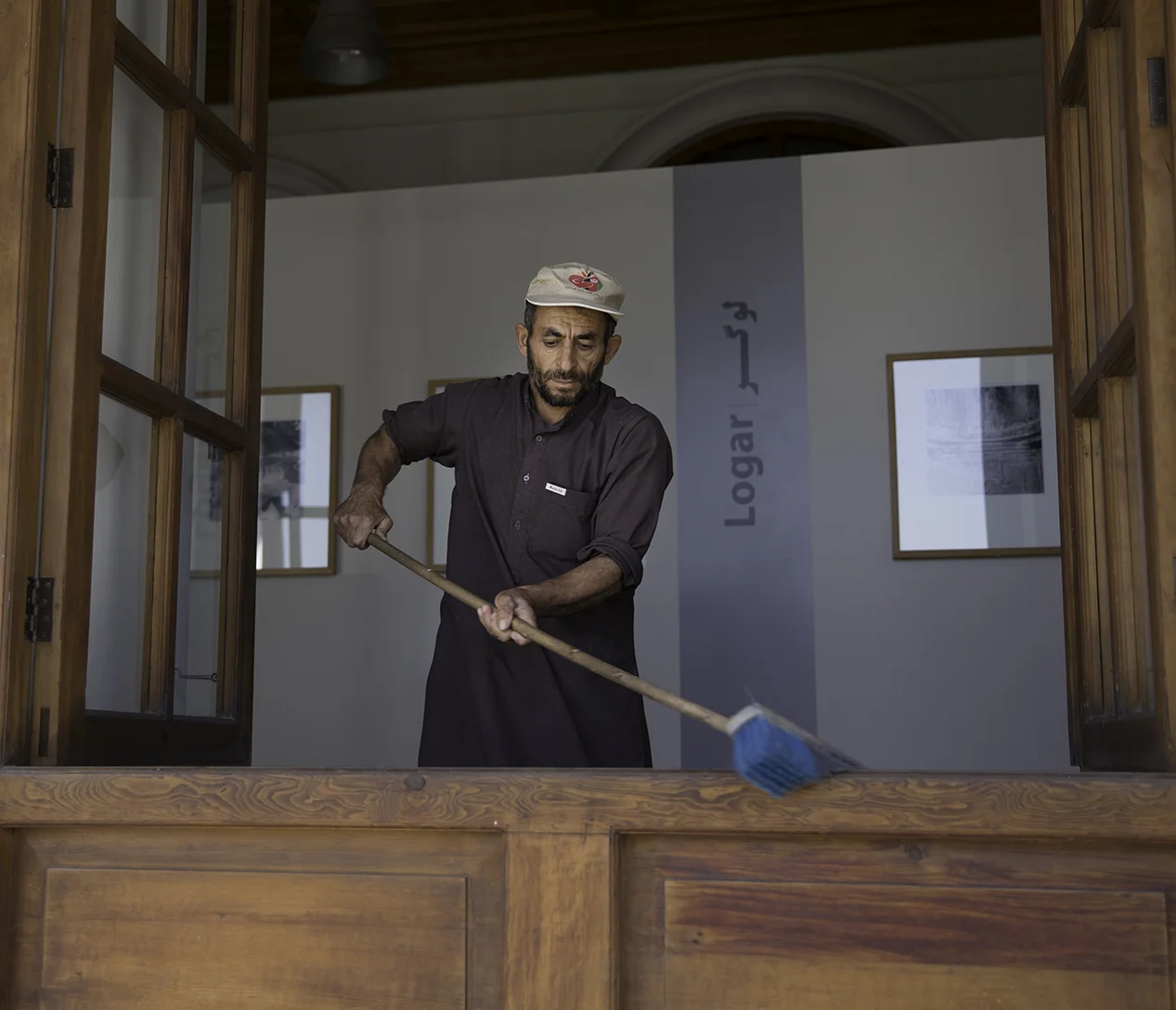 An employee sweeps the window ledge inside a gallery and exhibition hall in Bagh-e Babur’s main pavilion. The gallery pictures were taken by Josephine Powell in the 1960’s of Afghanistan’s historic monuments.