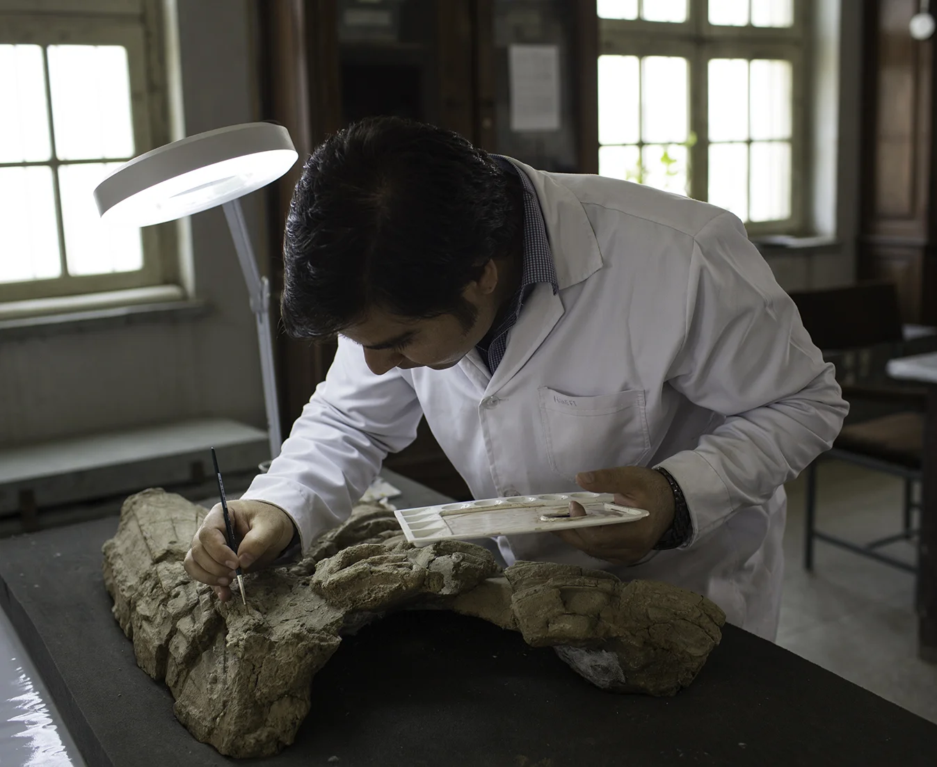 Conservator Ghufran Hanifi stabilizes the coloring of the robes on a clay sculpture excavated from Surkh Kotal in Baghlan