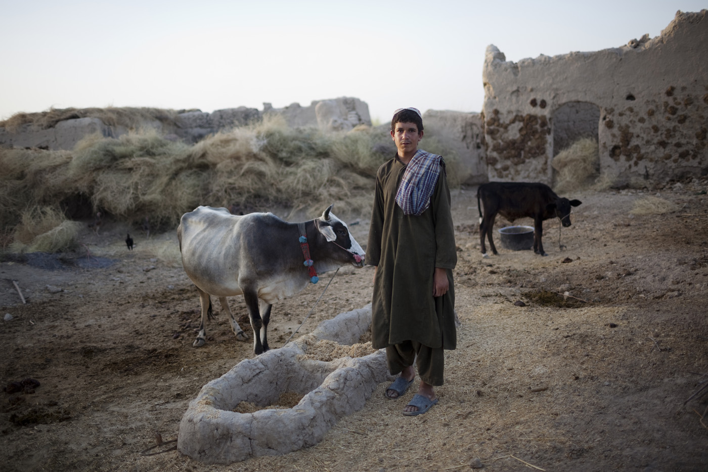 August 2009: An Afghan farmer stands outside his home as a U.S. Marine patrol walk past in Khan Neshin, Helmand province.
