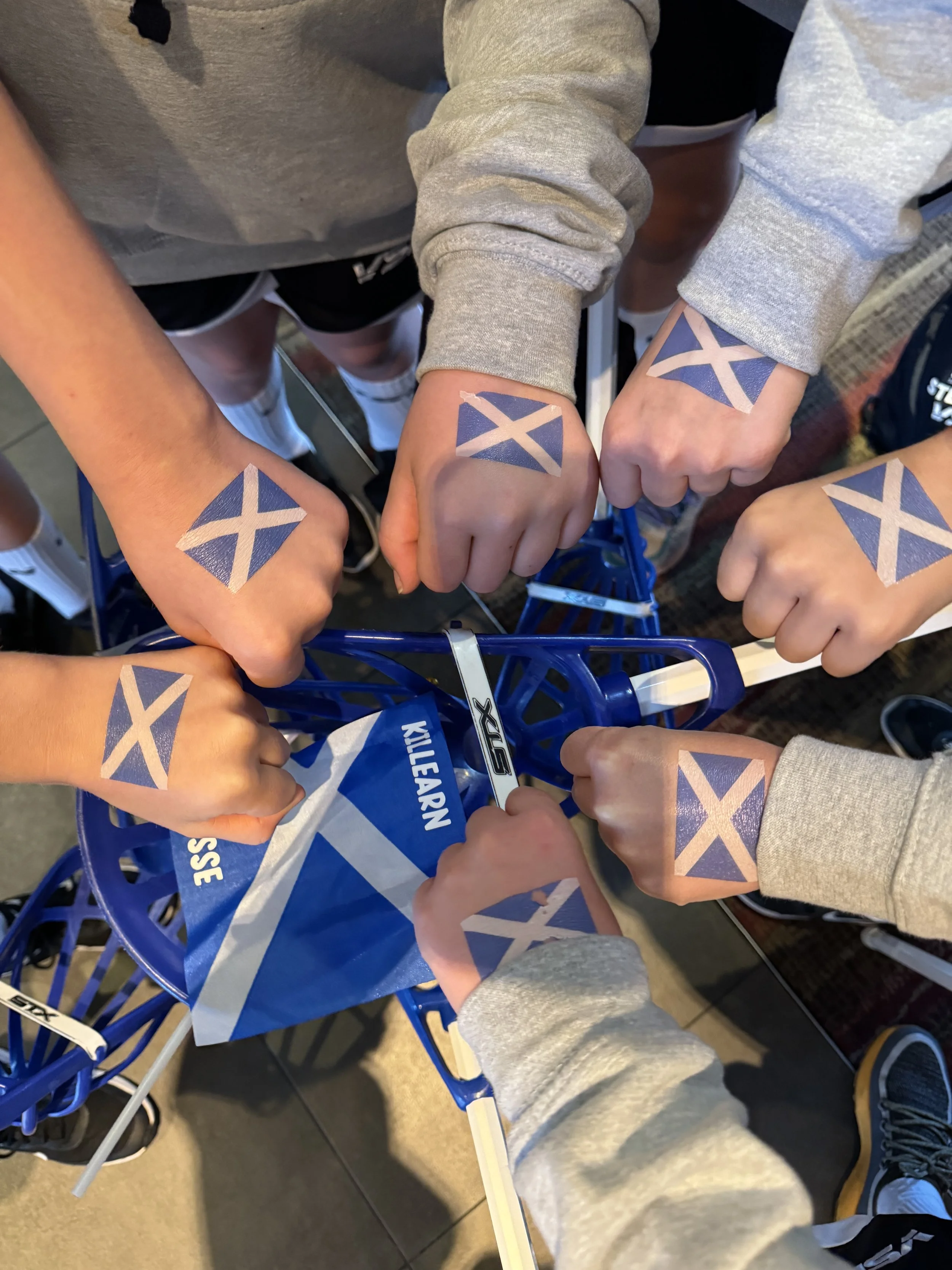 Many hands being put into the middle with Scottish flags on them