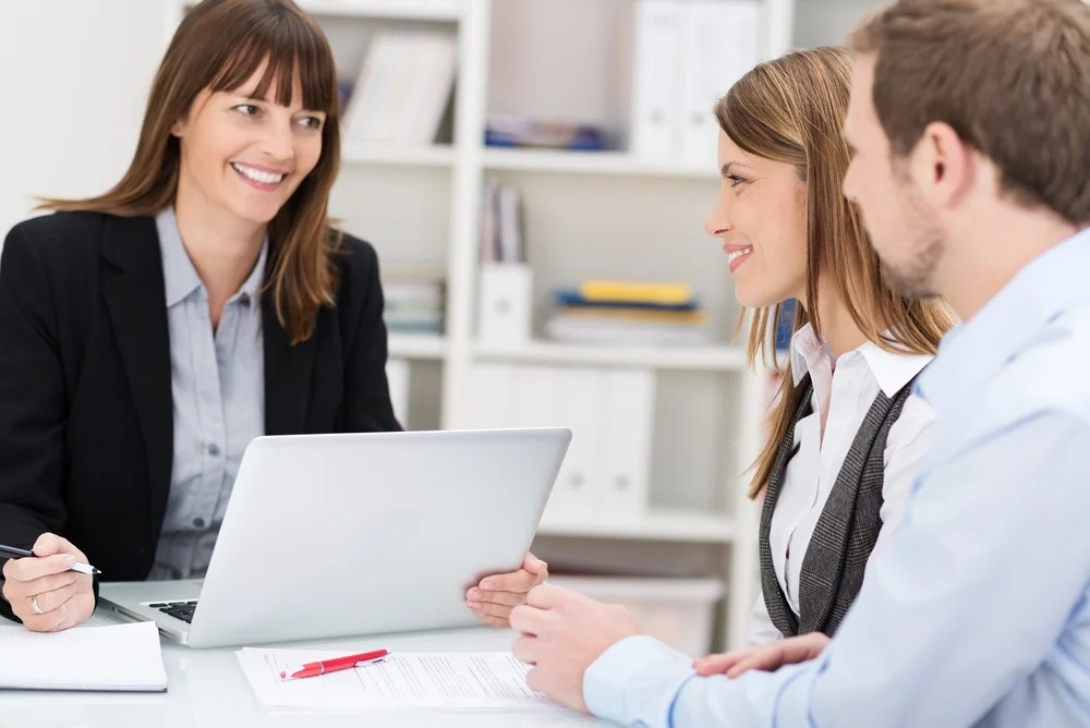 Young couple sitting in an office talking to a woman broker or investment adviser.jpg