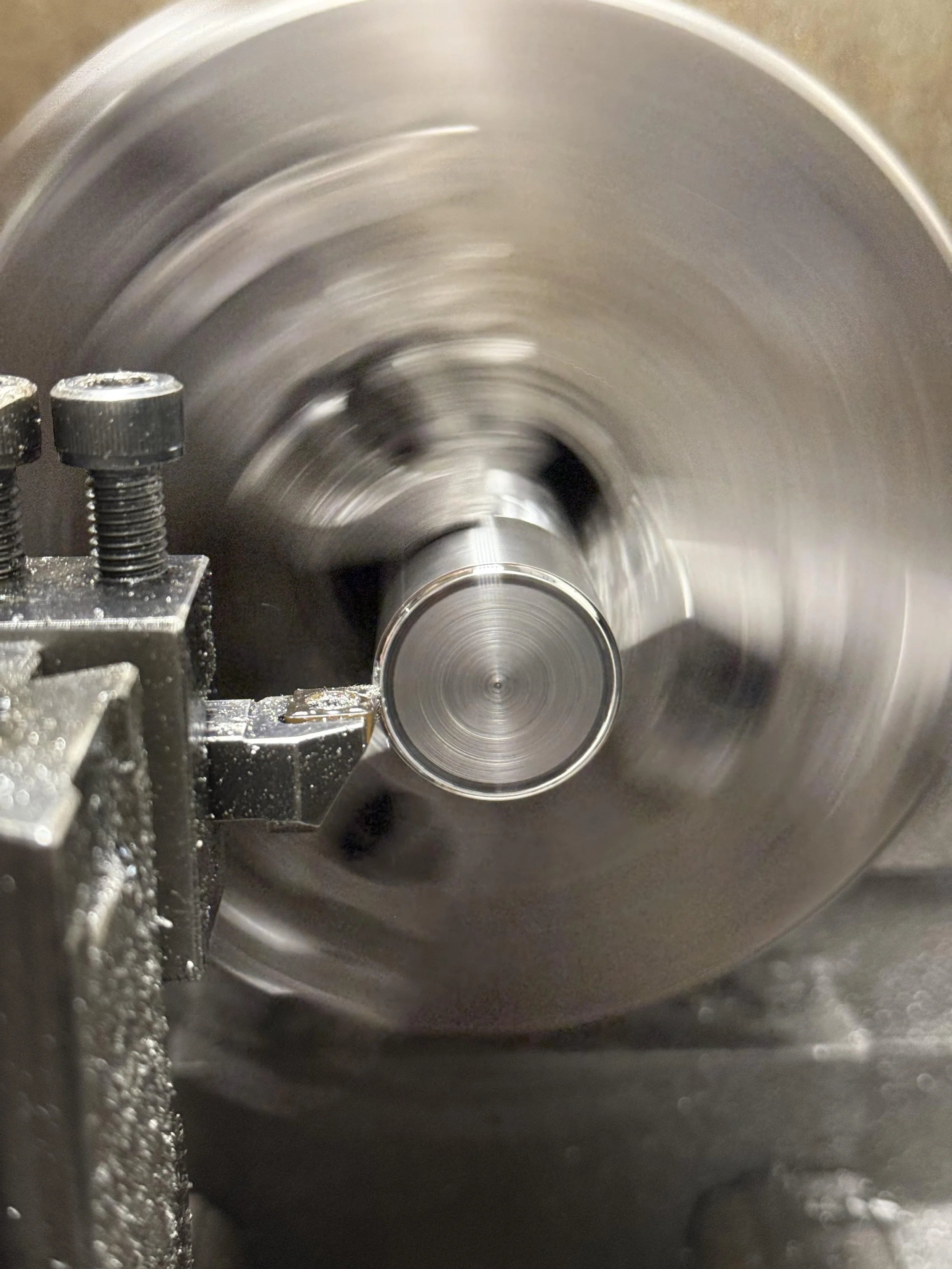 Lathe machine in operation, machining a cylindrical metal part at high speed