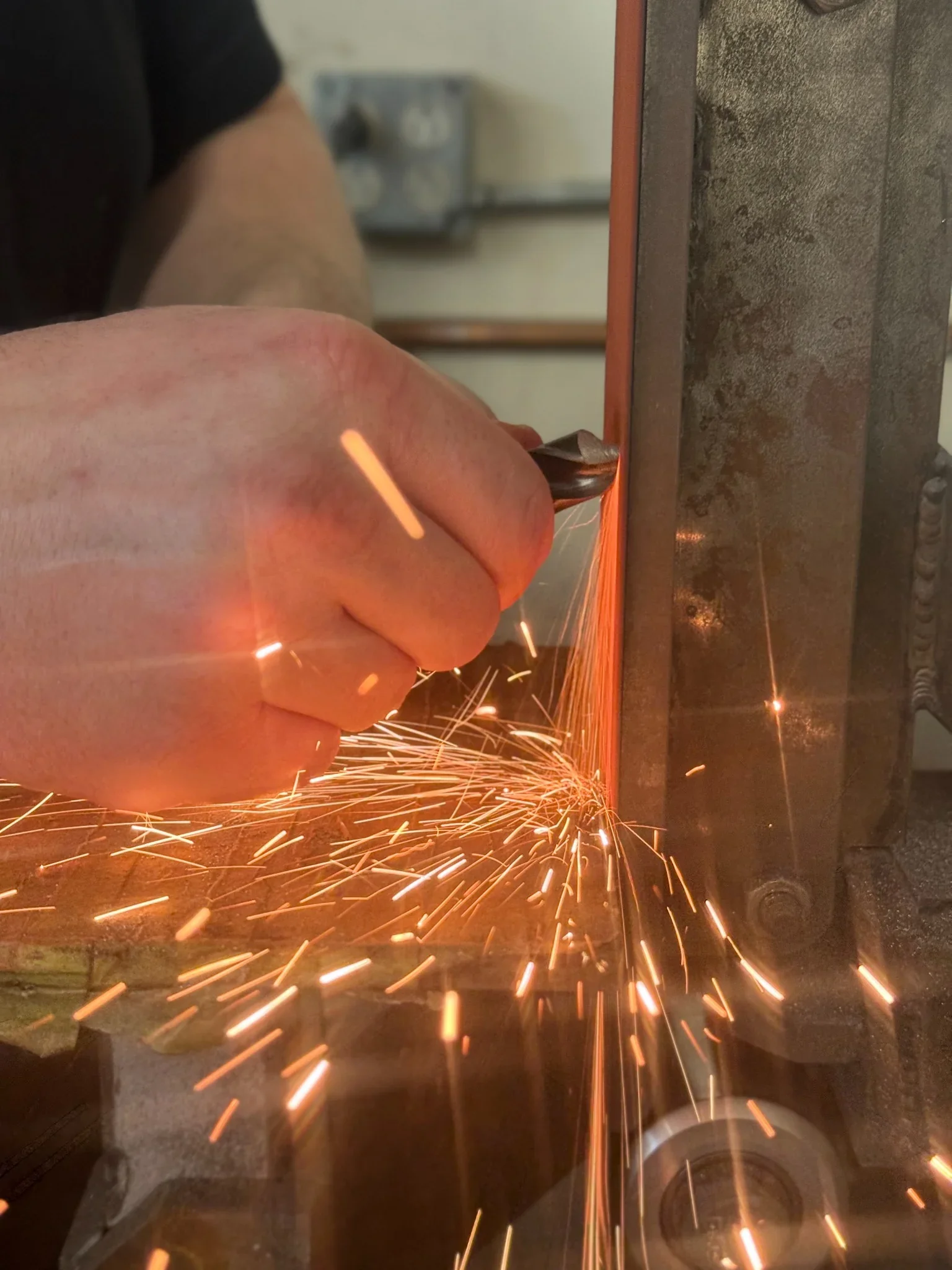 Close-up of precision metal grinding with sparks during hand finishing of steel components in a machine shop