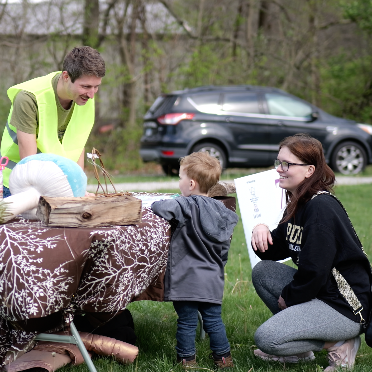 A volunteer engaging a young guest at an activity station during a community event