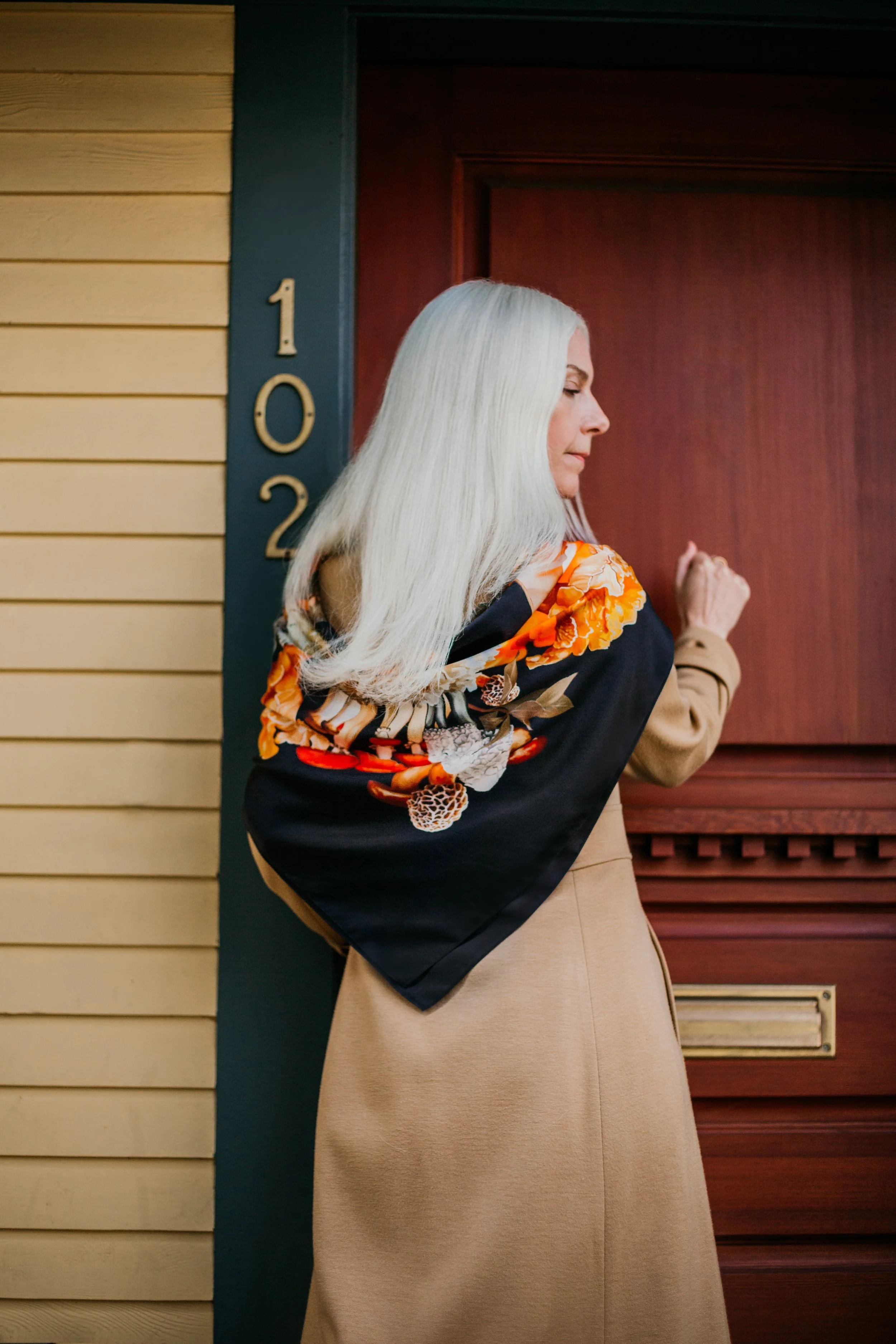 UNITY - in Black - designer silk scarf — woman wearing the scarf at a doorway, side view