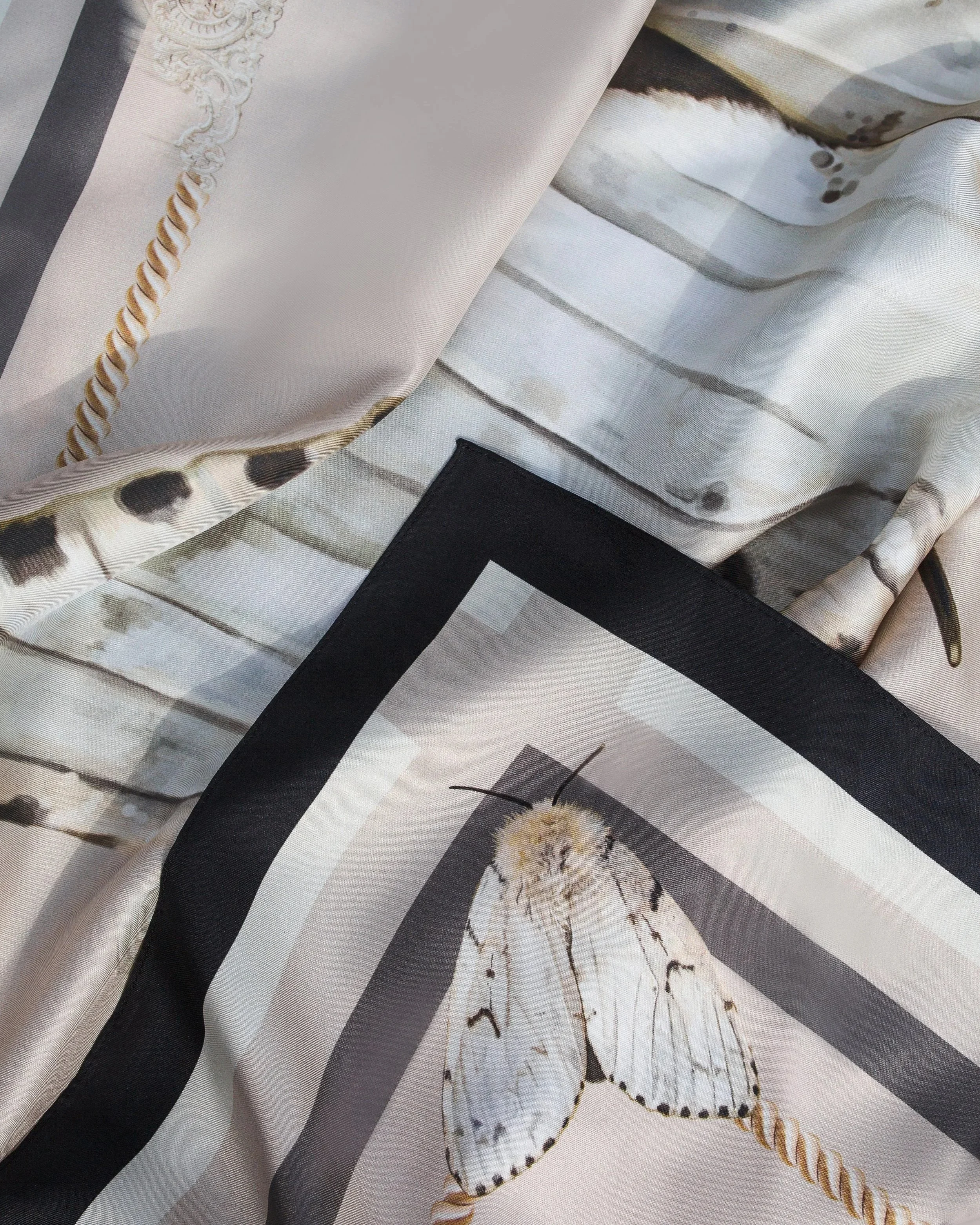 Close-up of a fabric featuring a butterfly illustration and decorative borders, likely part of a printed textile or scarf.