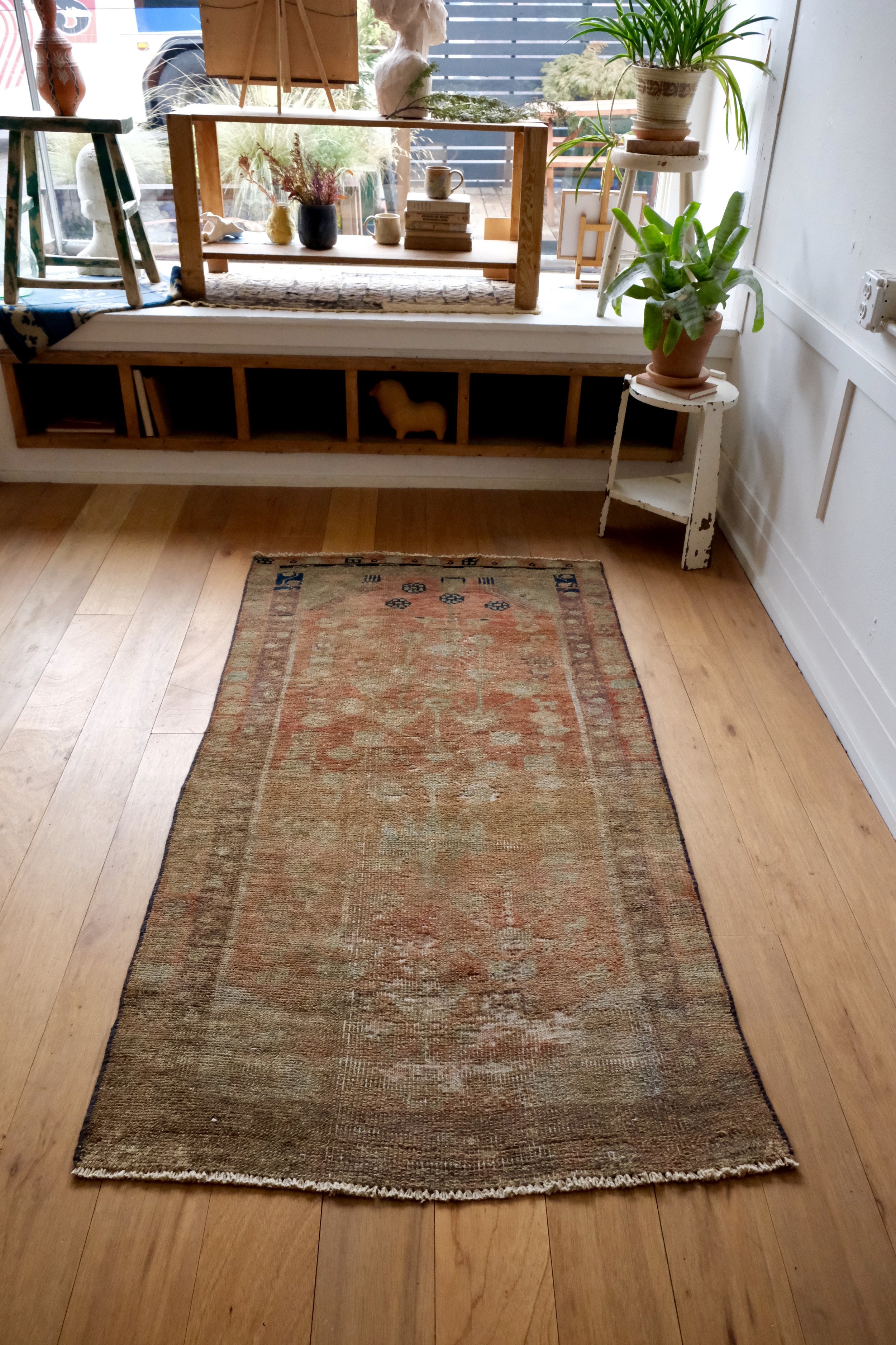 vintage Turkish rug in earthy persimmon and sand colors, displayed in the studio