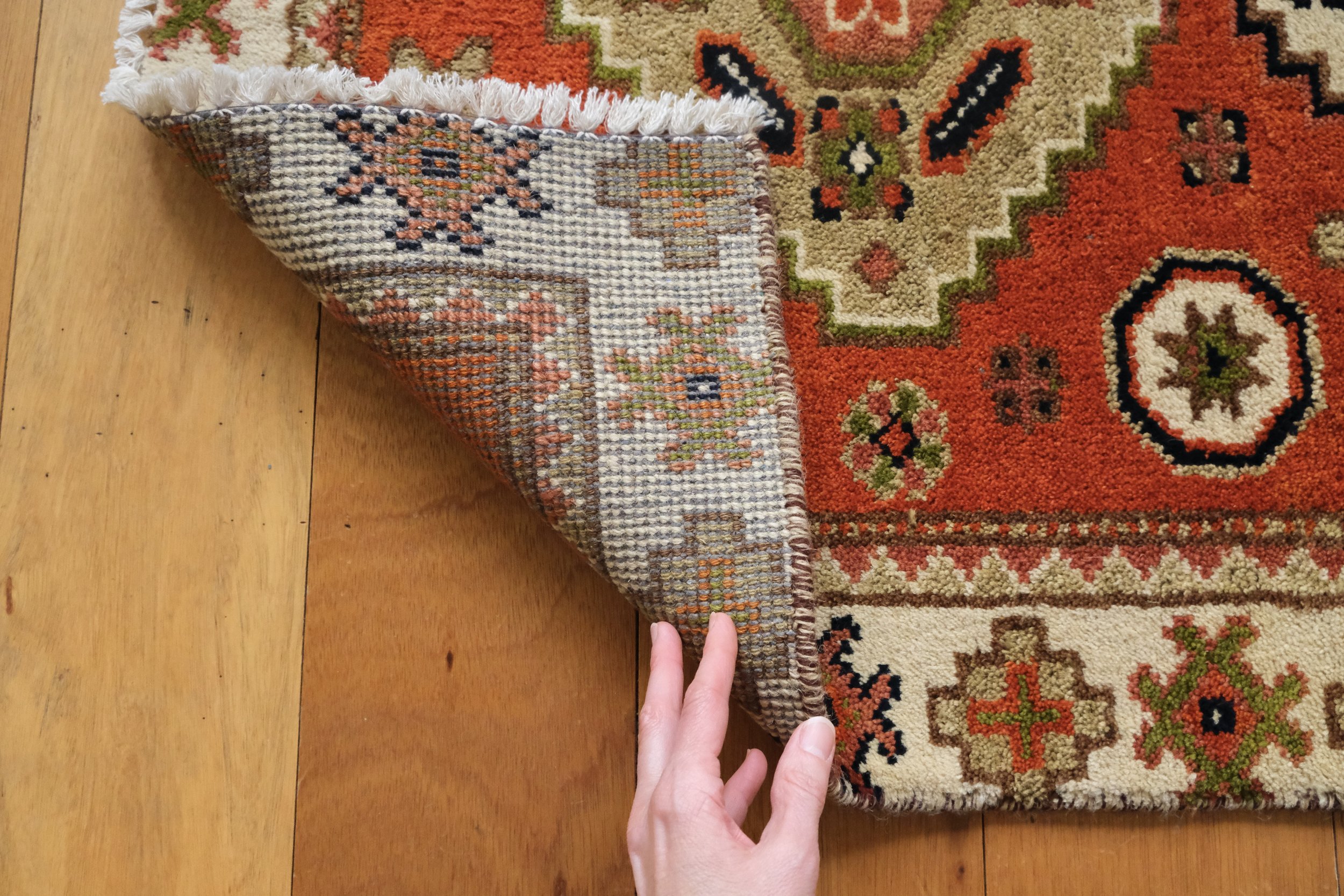 the corner of the turkish rug is flipped showing the unique handmade hand knotted backside of the rug