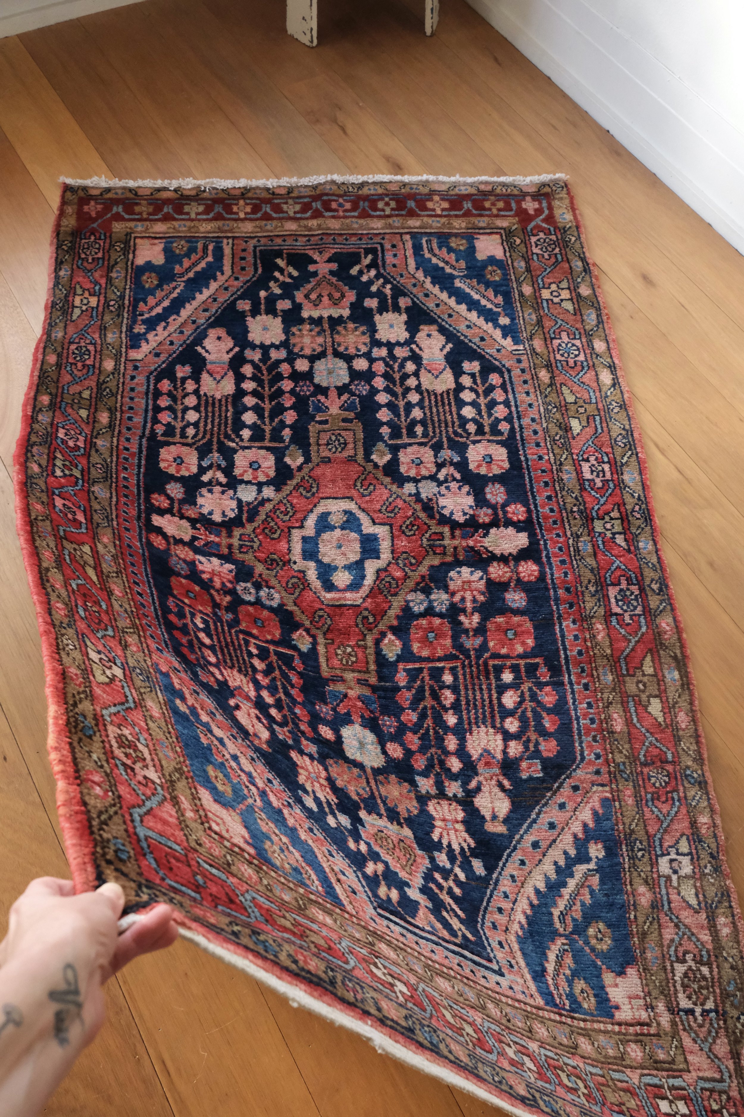 Anna holds the corner of the vintage Hamadan rug showing its lovely drape