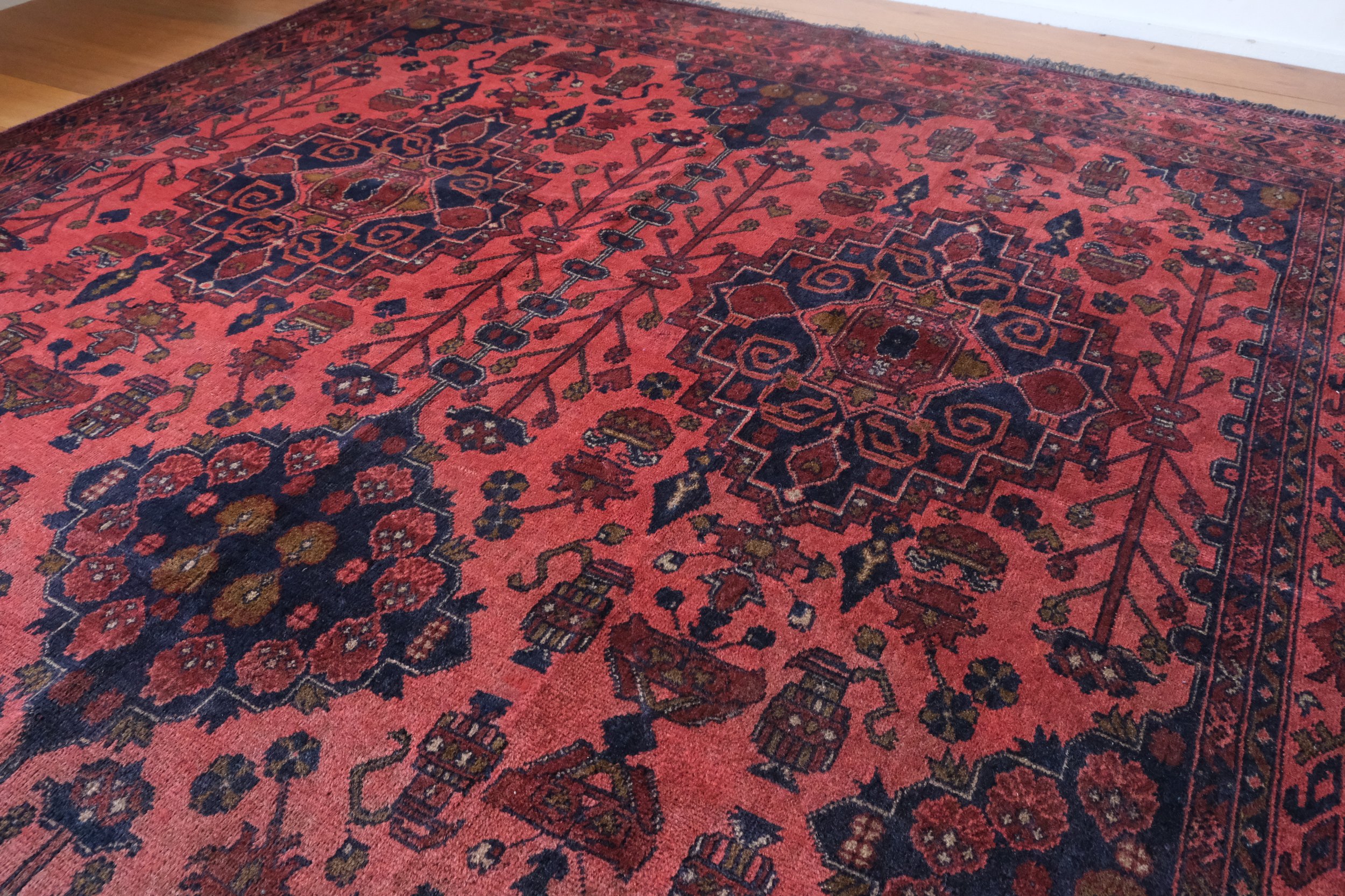 close-up view of rug pattern showing vases with flowers and vines