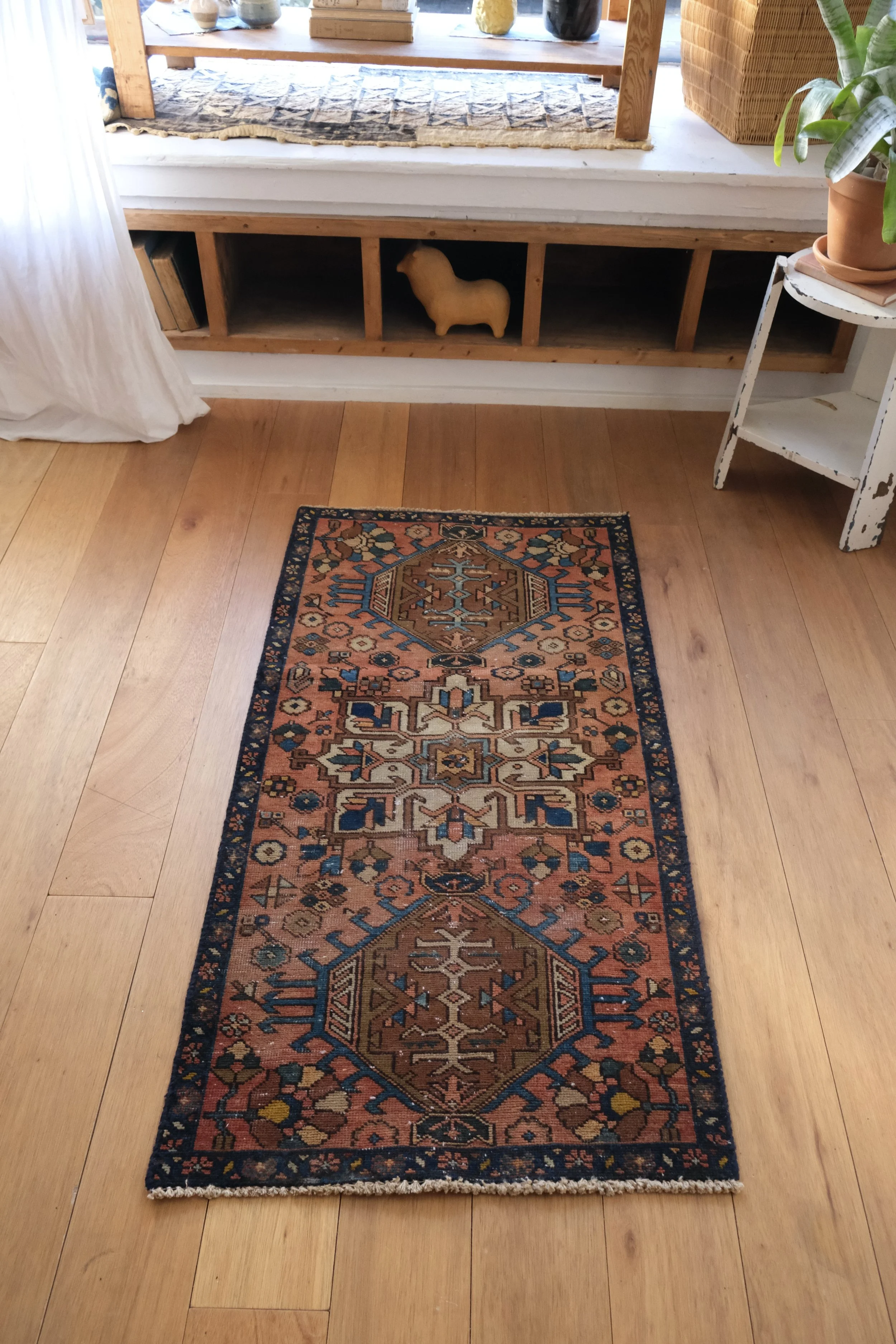 vintage Persian Karache rug with terra cotta field and rich colors shown displayed lengthwise