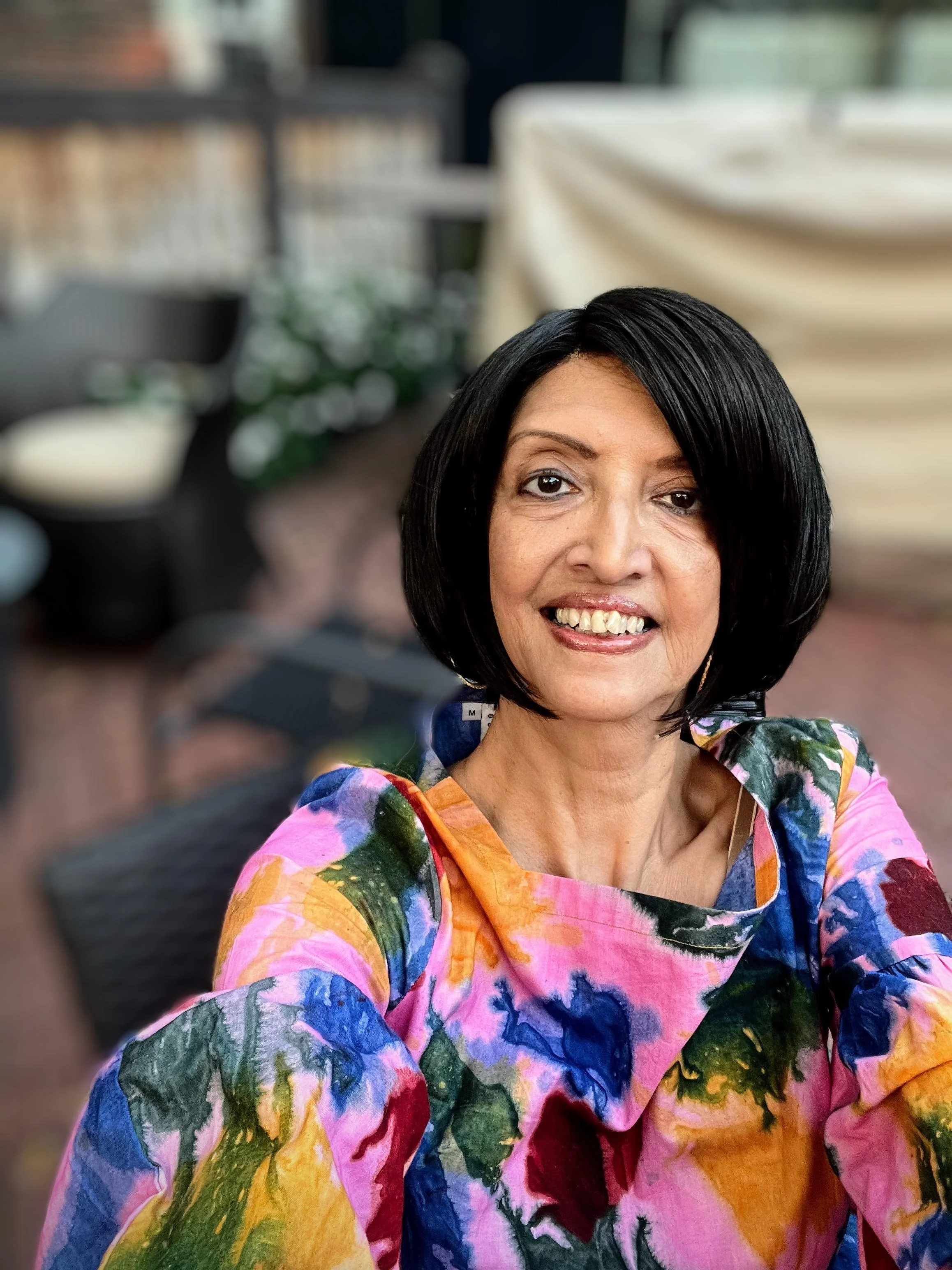 Sangeeta Ray smiling, wearing colorful print blouse.